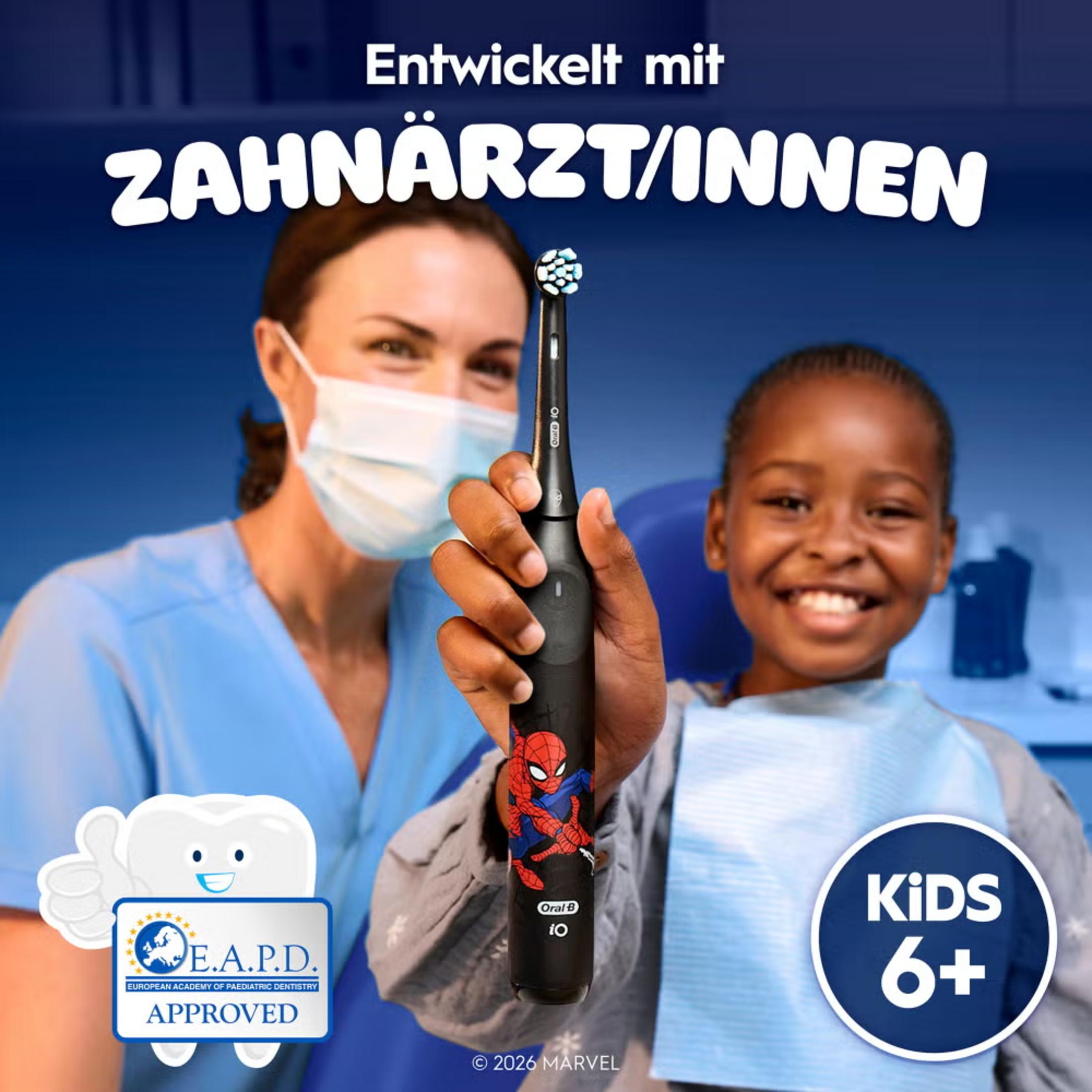 Ein Kind mit zahnärztlicher Untersuchung, gehalten von einer Ärztin mit Spiderman Zahnbürste.
