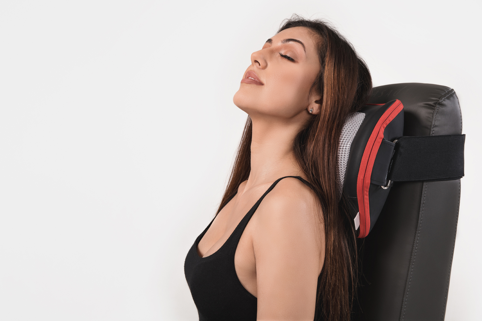 Kobieta opiera się do tyłu z zamkniętymi oczami, używając poduszki na kark.