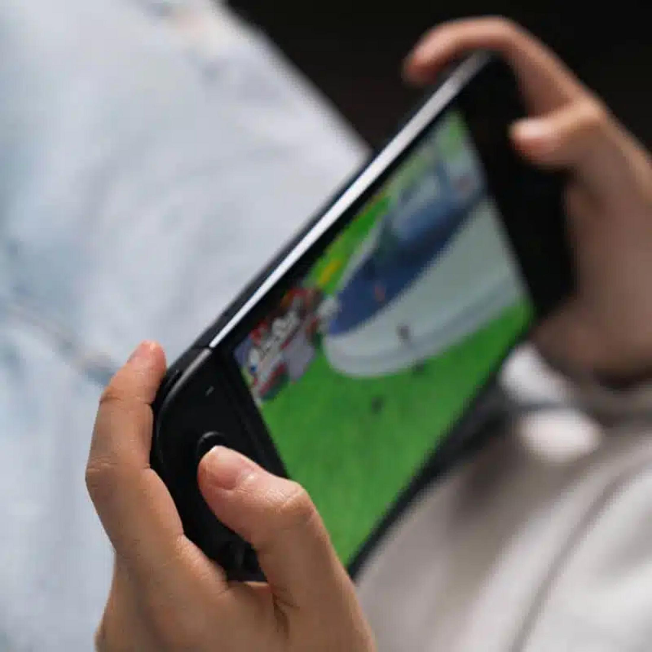 Hände halten ein schwarzes Videospielgerät mit einem grünen Bildschirm.