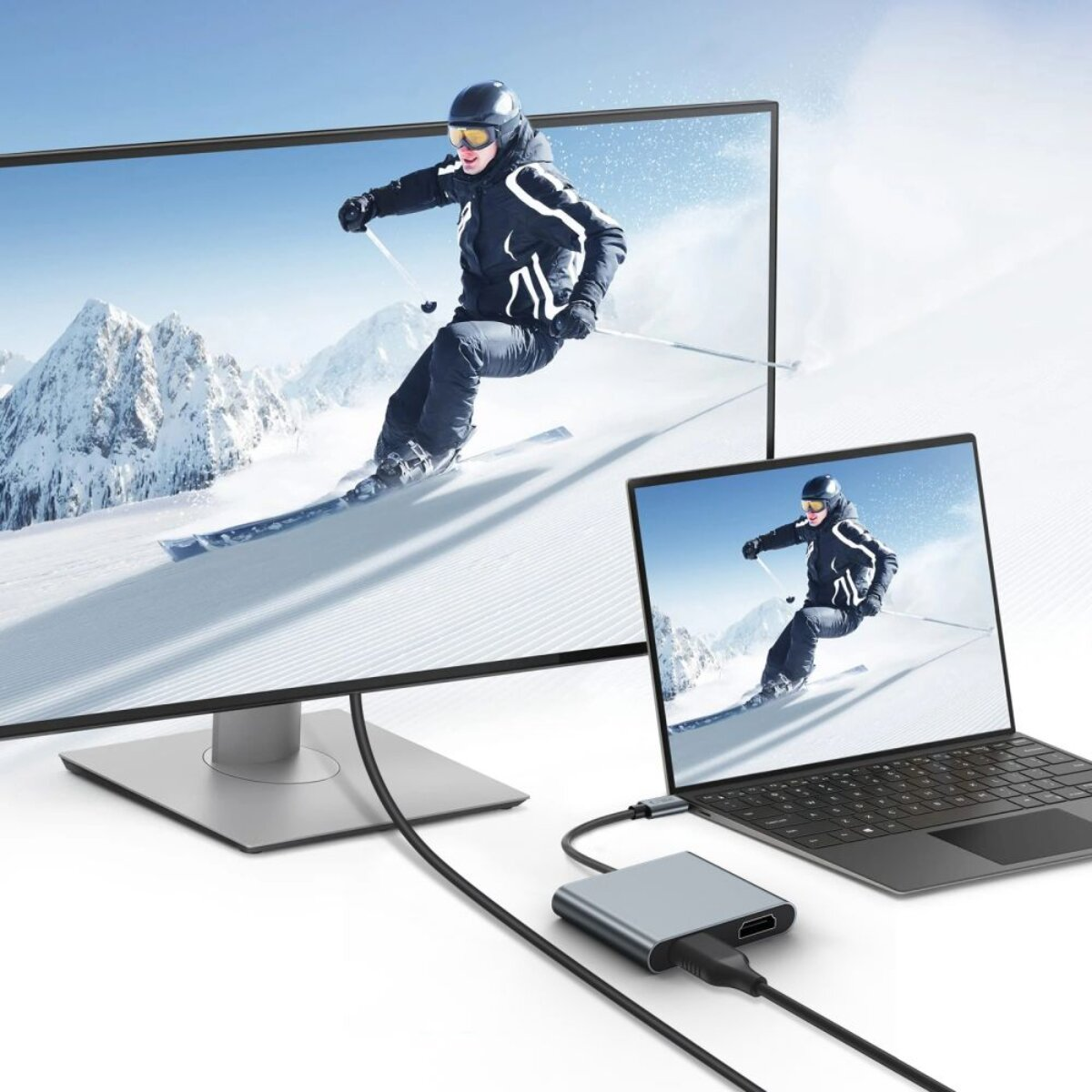 Uno sciatore su una montagna visualizzato su un monitor e un laptop.
