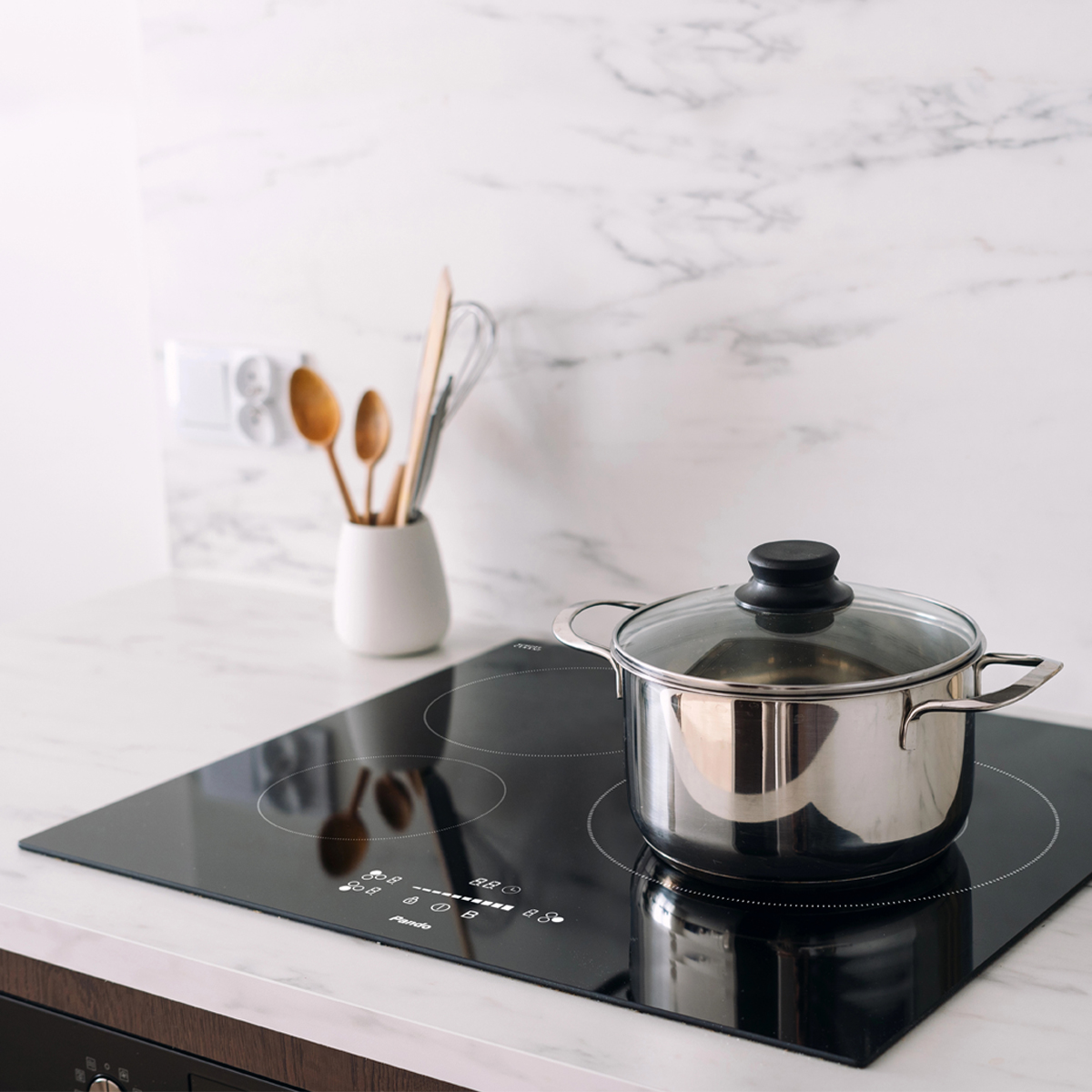 Una olla con tapa de cristal sobre una placa de inducción.