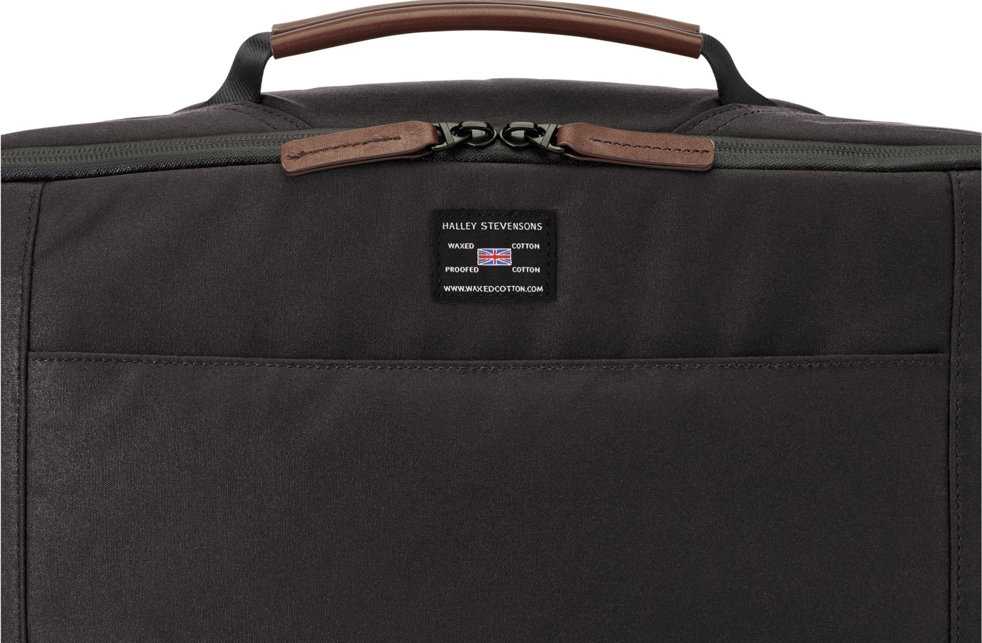 Dunkler Rucksack mit braunen Lederdetails und einem Etikett mit der britischen Flagge.