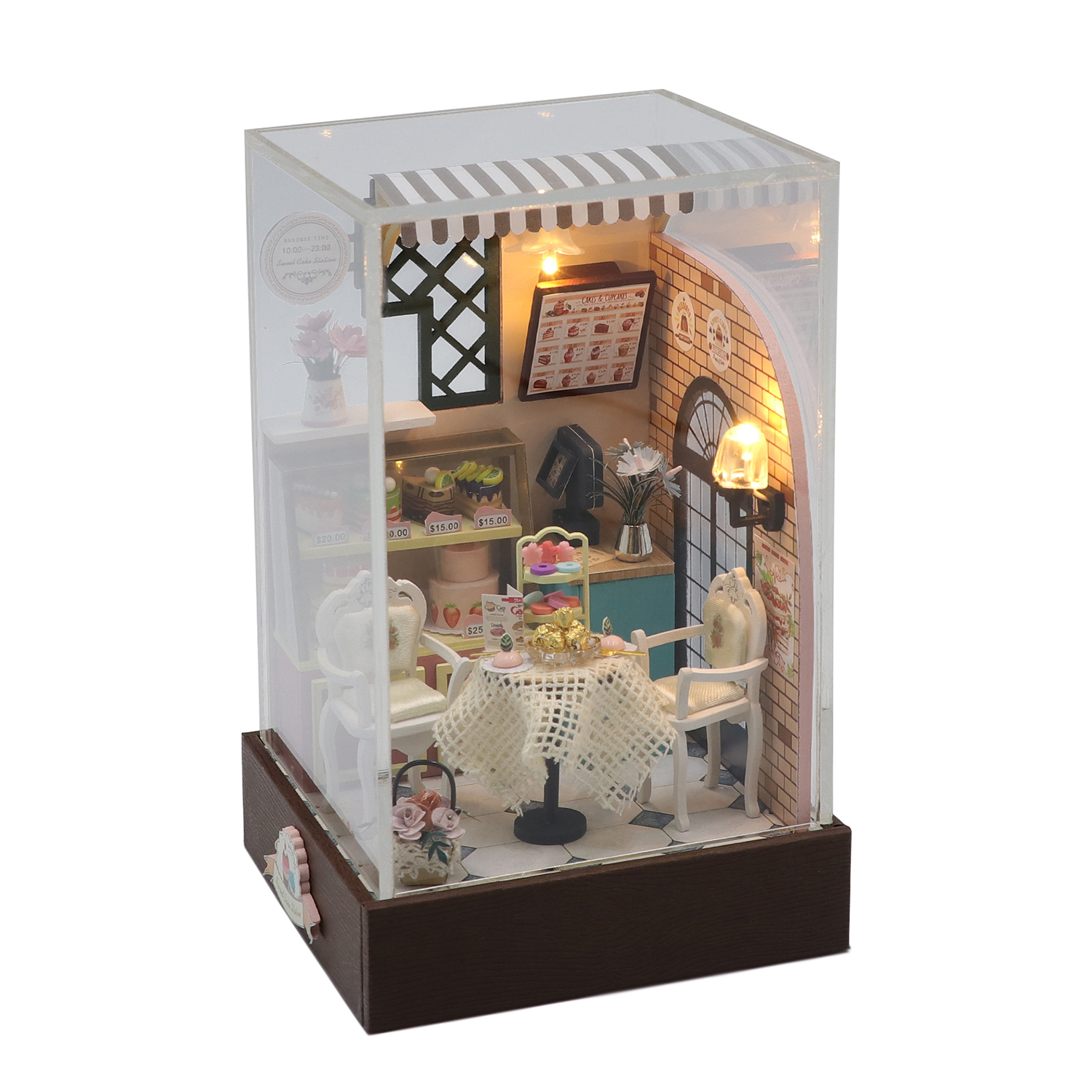 Una scena di caffè in miniatura con tavoli, sedie, torte e luci.