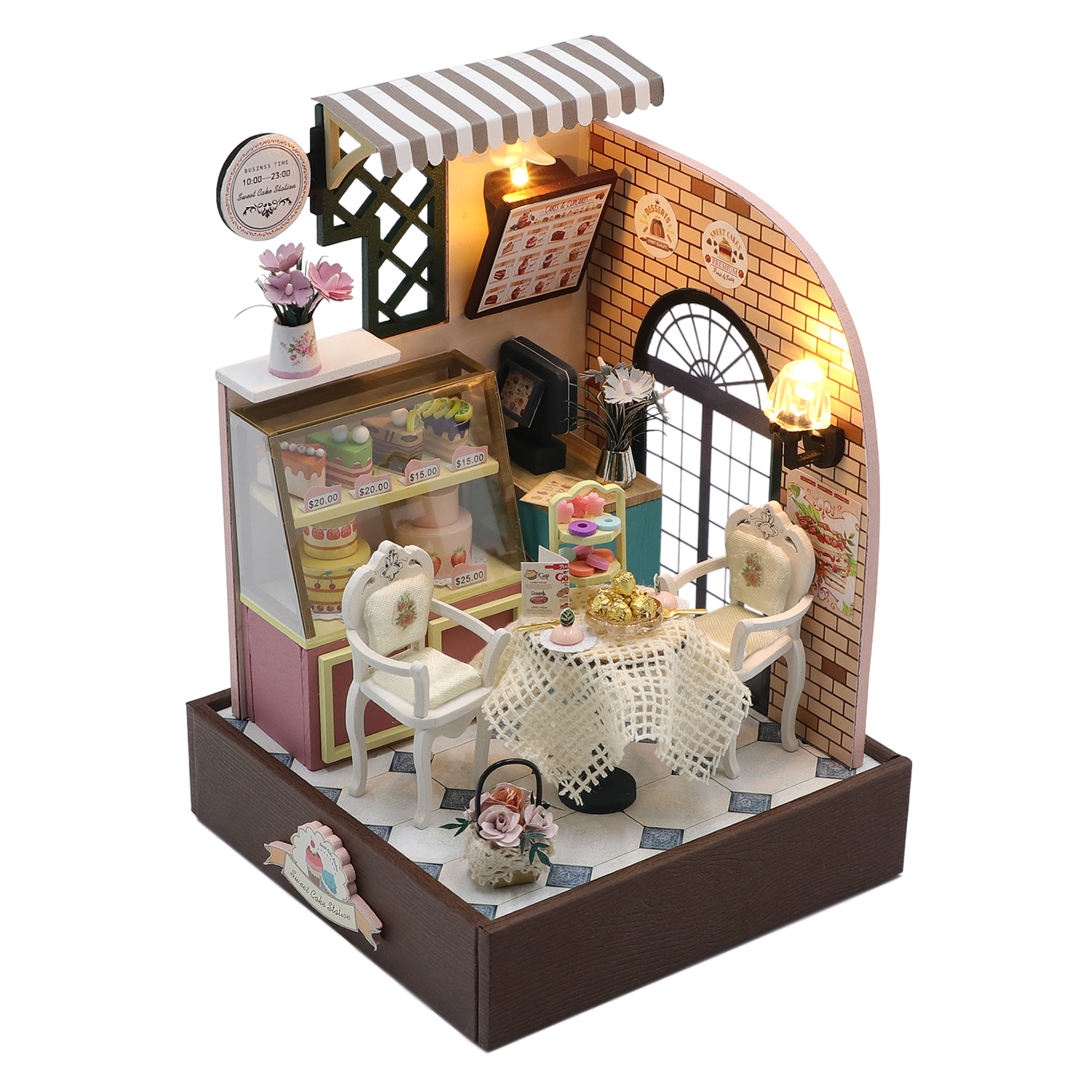 Pasticceria in miniatura con vetrina, tavolo, sedie e parete in mattoni.