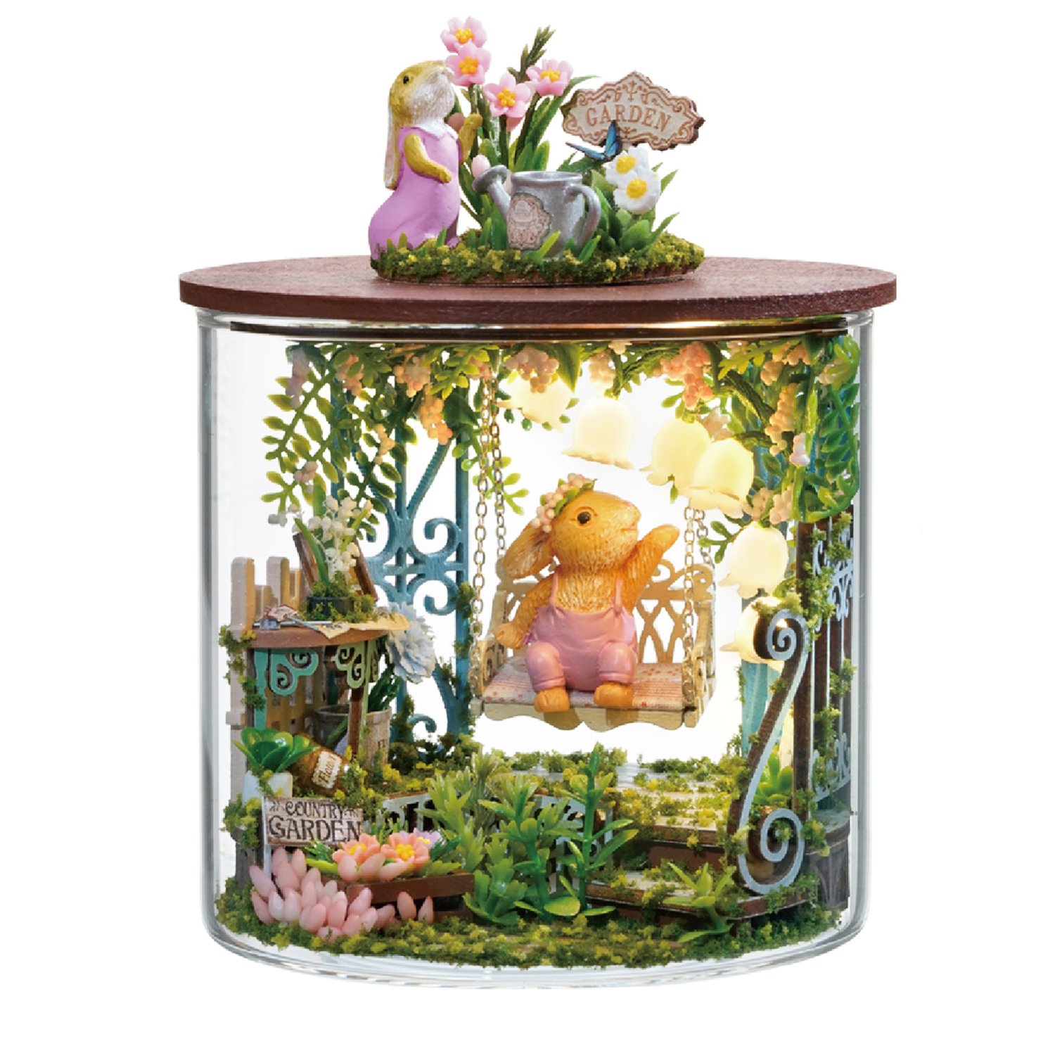 Scena di giardino in miniatura con conigli, altalena e fiori in una cupola di vetro.