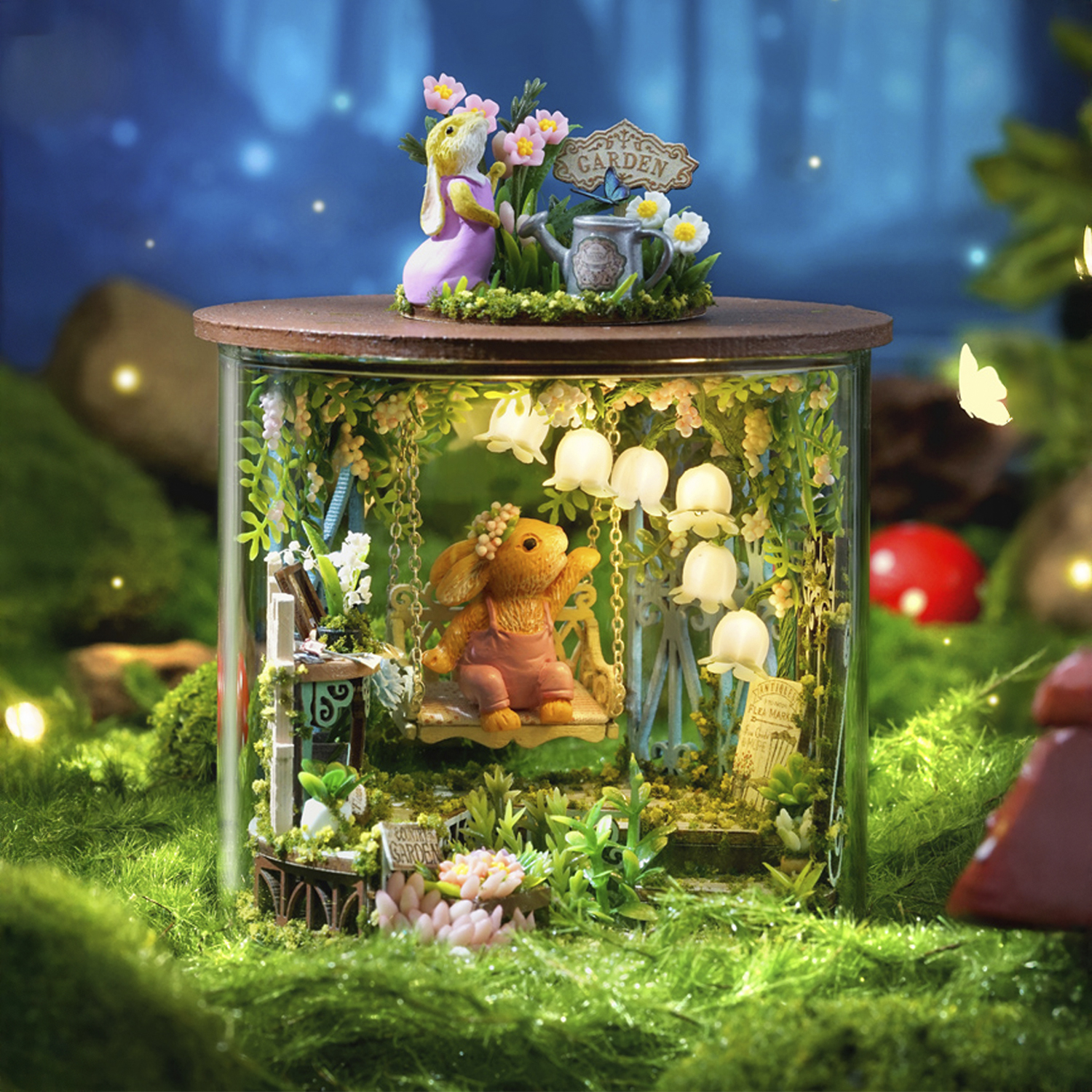 Un giardino in miniatura con conigli su un'altalena dentro un contenitore di vetro.