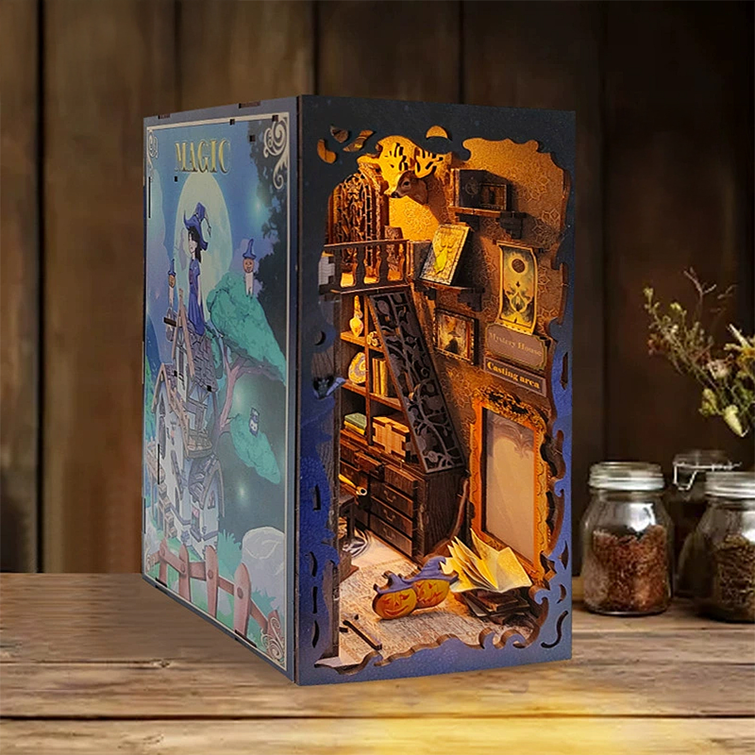 Un diorama illuminato con streghe, magia e libri su un tavolo di legno.