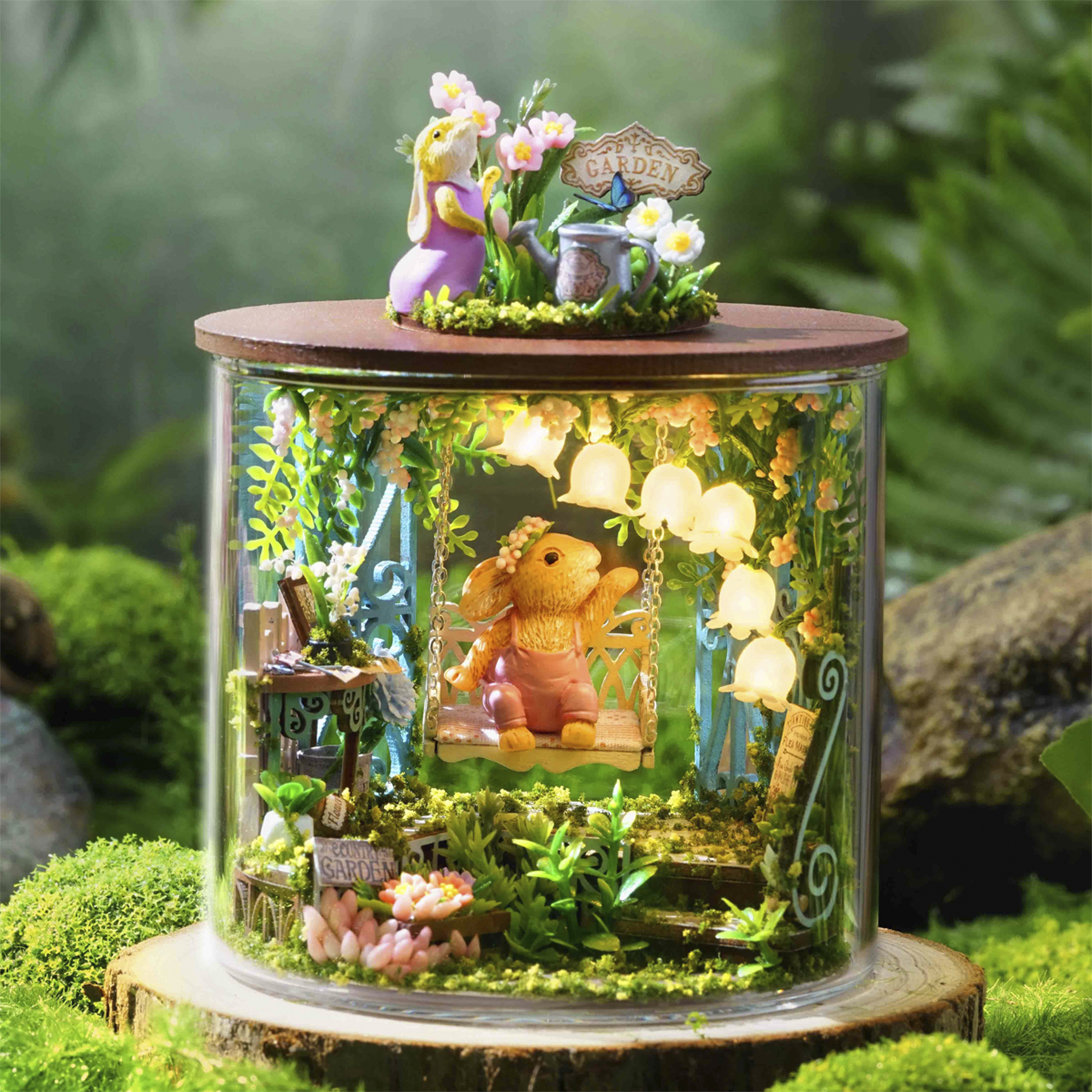 Diorama da giardino in miniatura con conigli e fiori, illuminato.