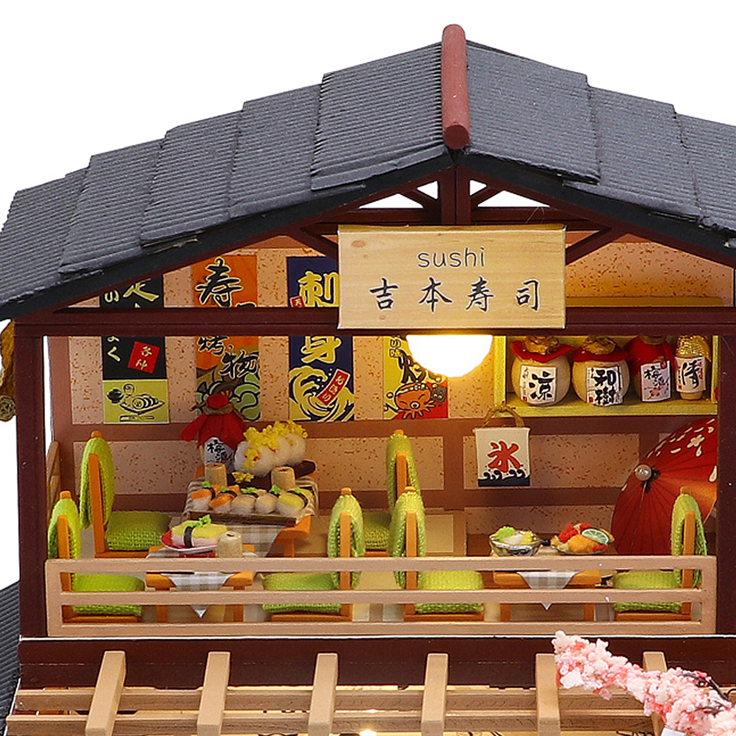 Ristorante di sushi in miniatura con tavoli, sedie, vassoi di sushi e decorazioni giapponesi.