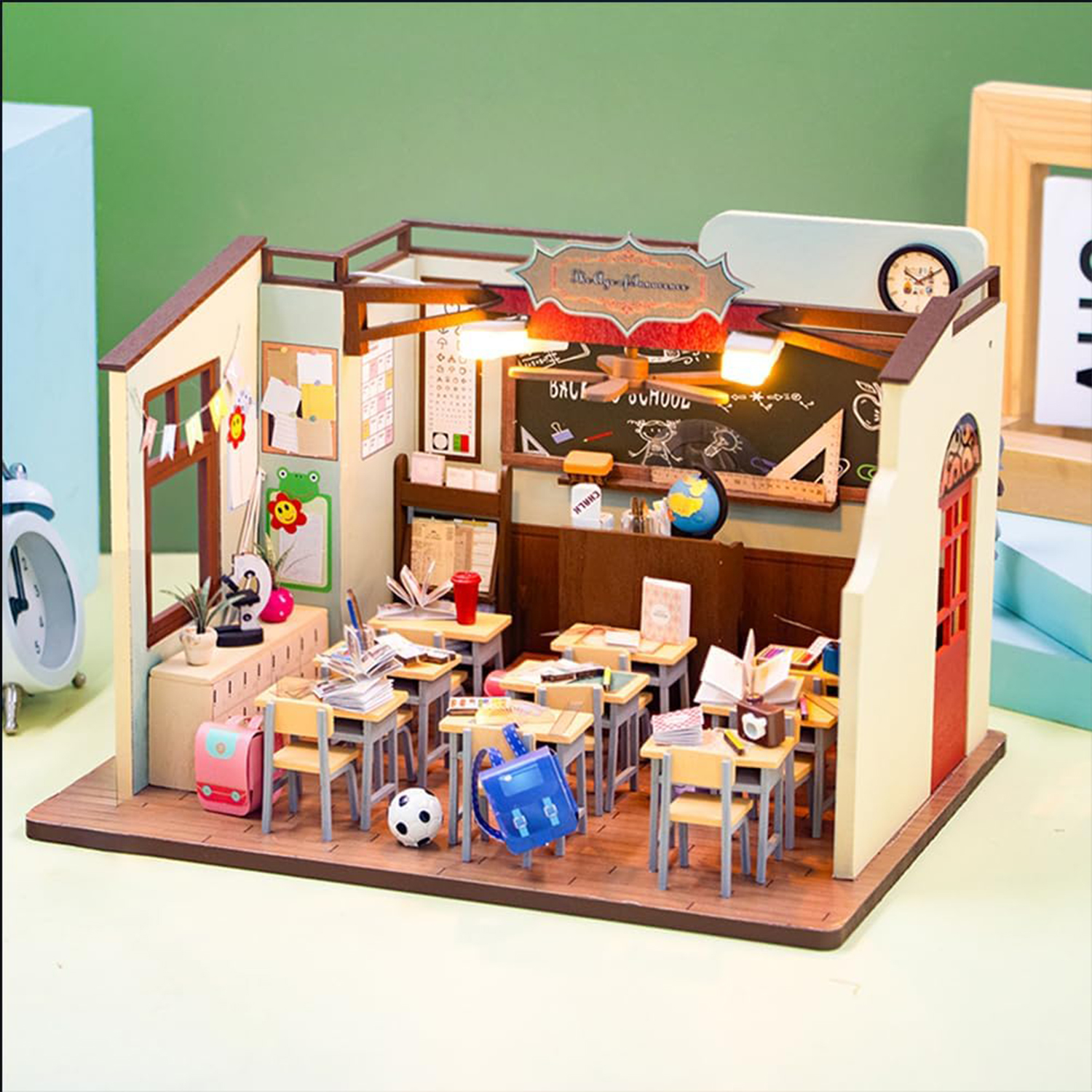 Aula in miniatura con scrivanie, lavagna e decorazioni.