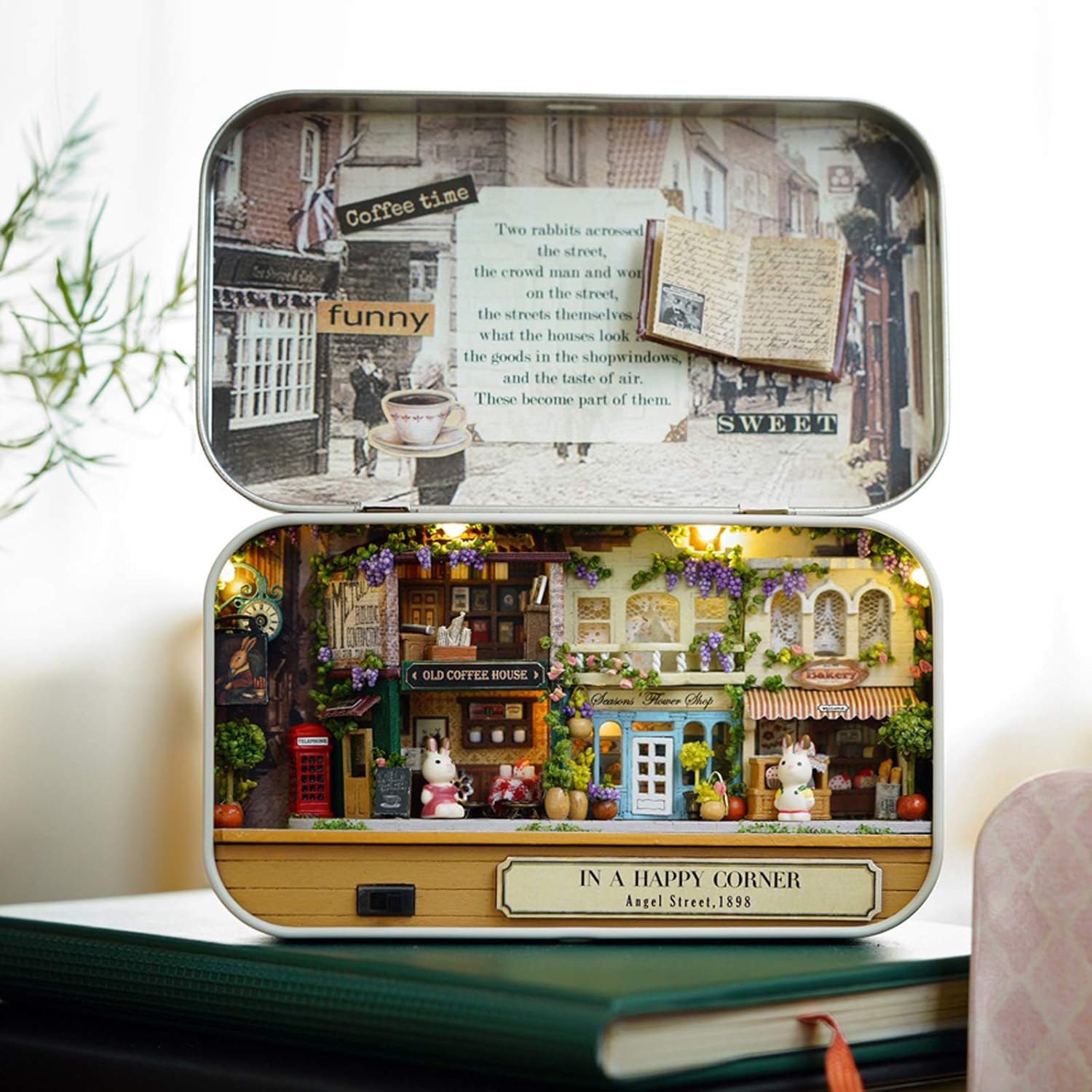 Diorama in miniatura di una scena di strada con figure di conigli e negozi in una scatola.