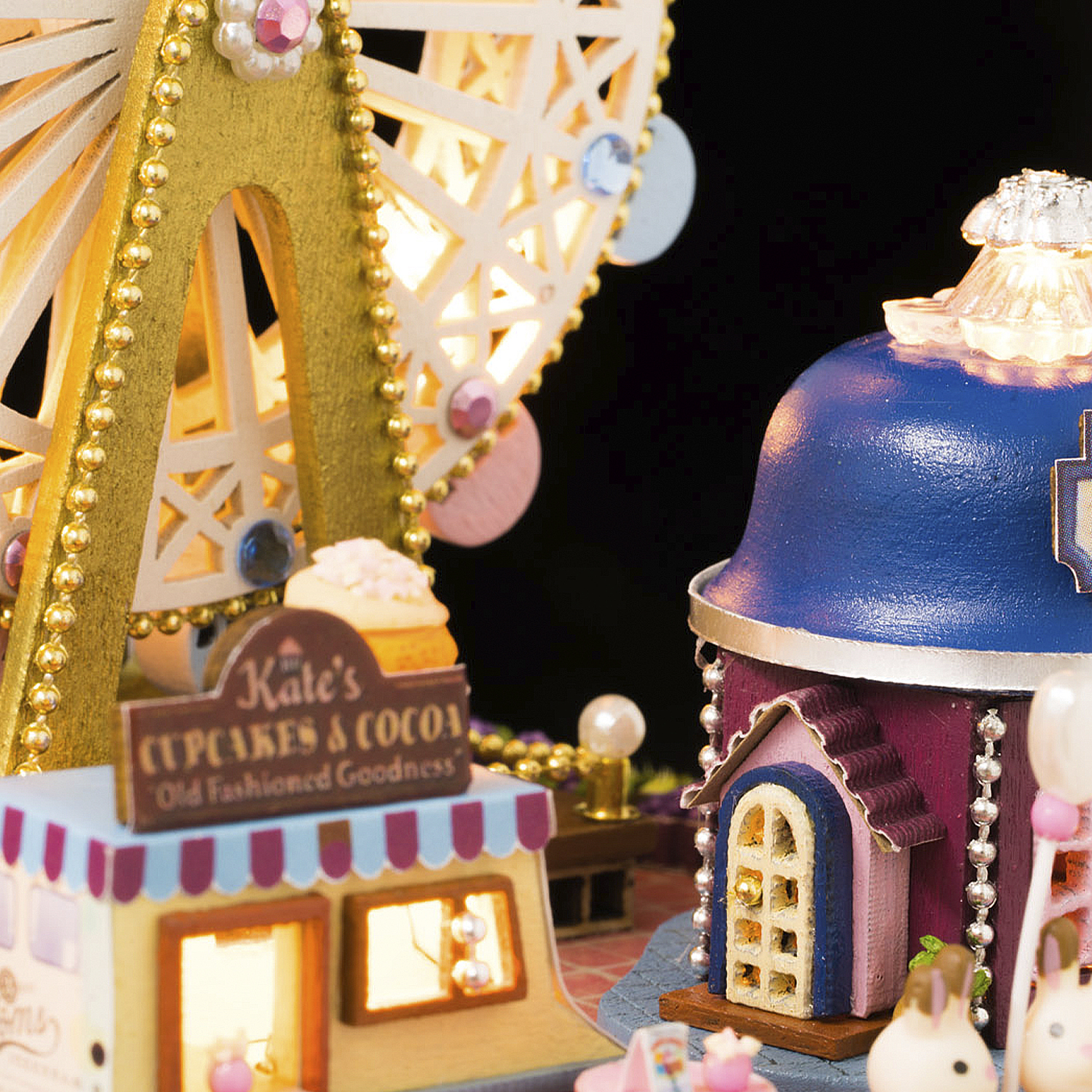 Ruota panoramica in miniatura accanto a una pasticceria e una casa con conigli.
