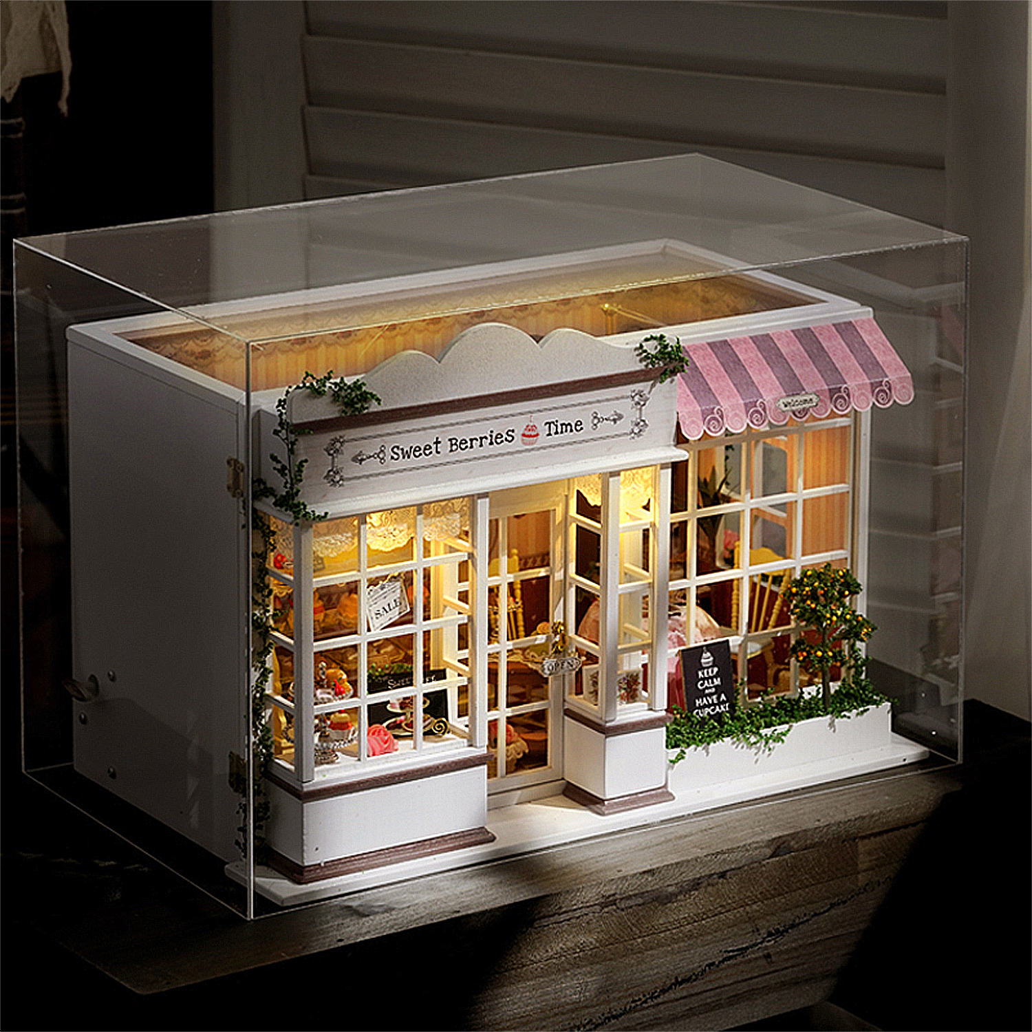 Negozio di dolci in miniatura con tenda a righe rosa e insegne.