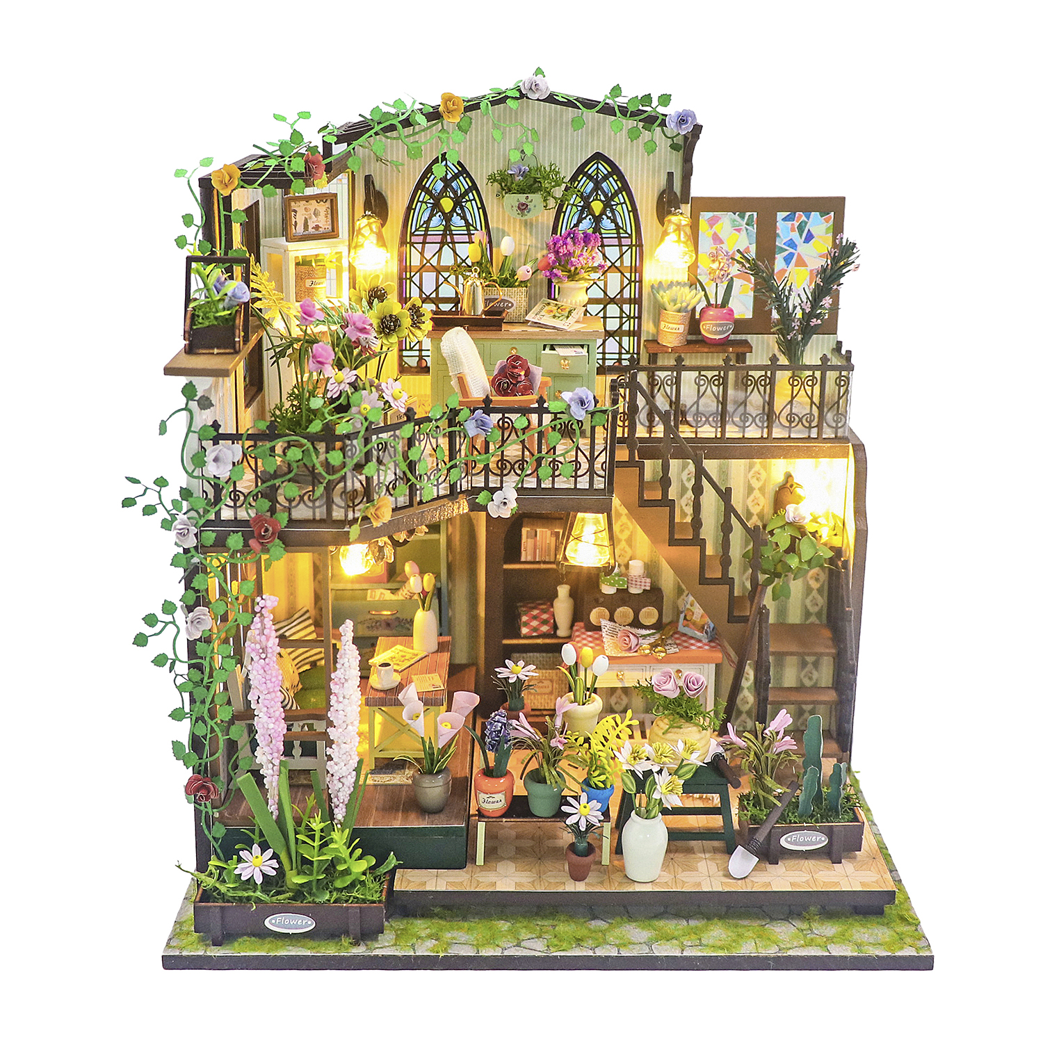 Una casa delle bambole dettagliata con fiori, piante e luci su più livelli.