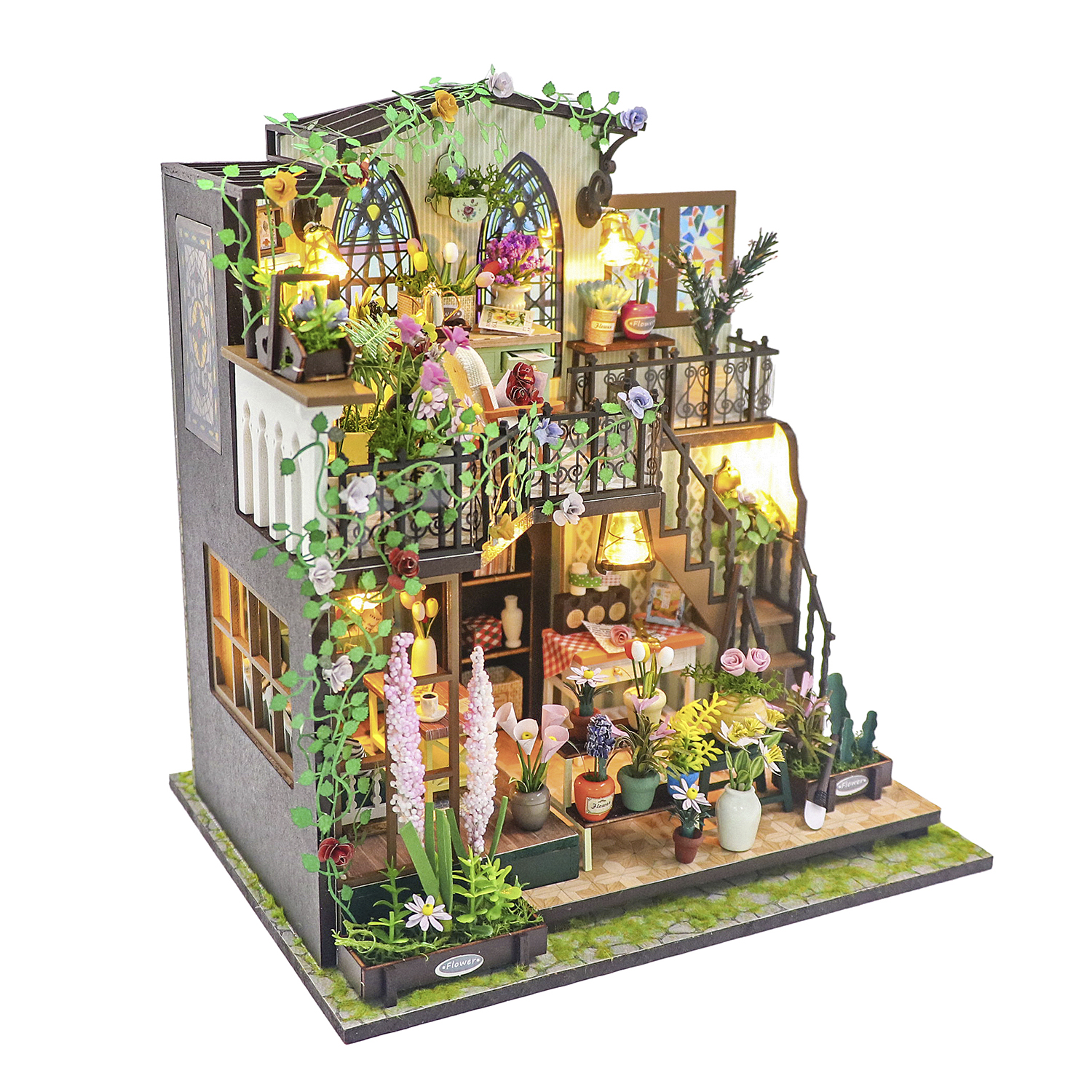 Casa in miniatura con molte piante, fiori e luci su più livelli.