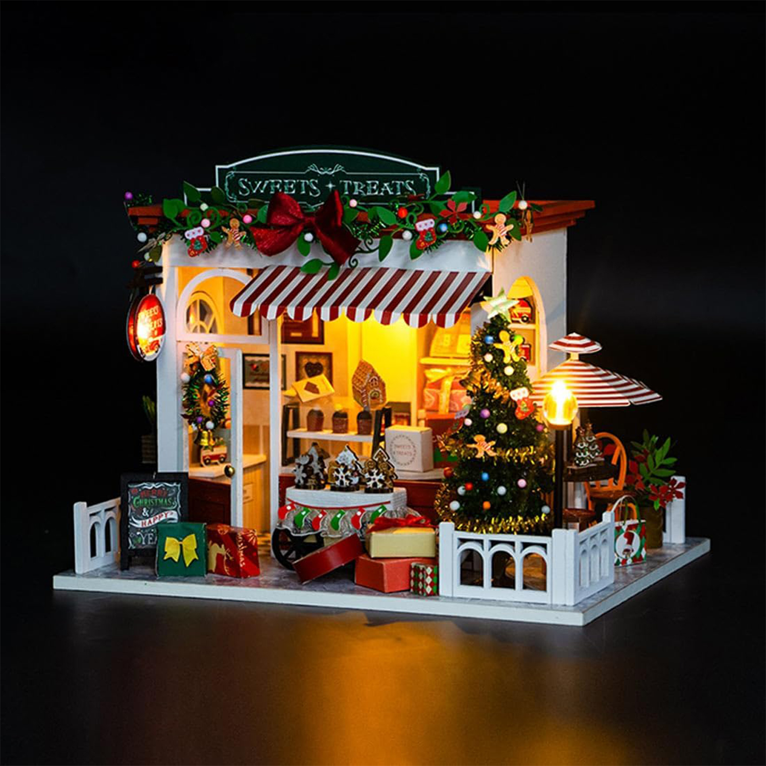 Un negozio in miniatura di dolci natalizi con albero, regali e luci festive.