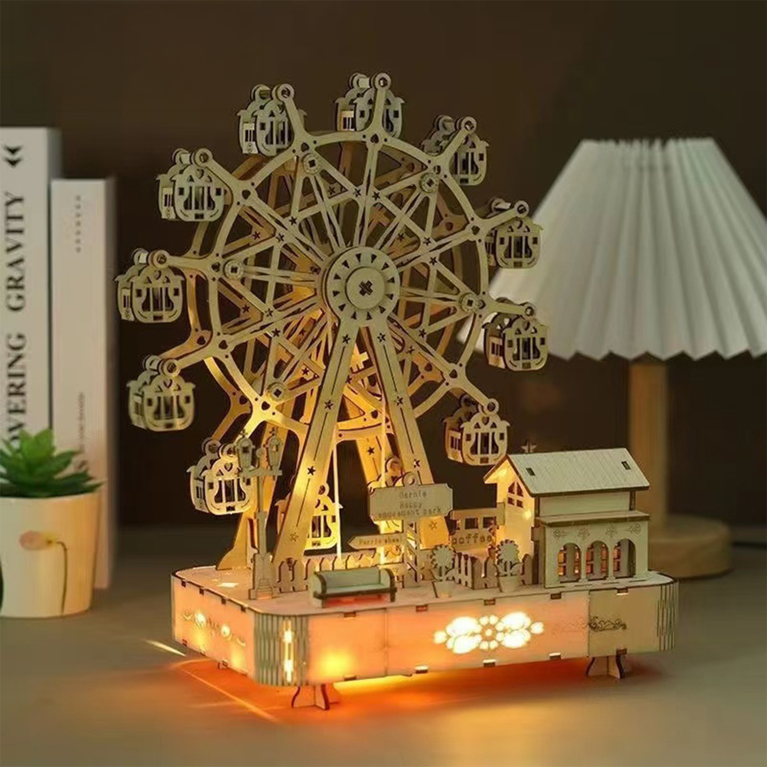 Un modello di ruota panoramica in legno con luci e un piccolo edificio sullo sfondo.