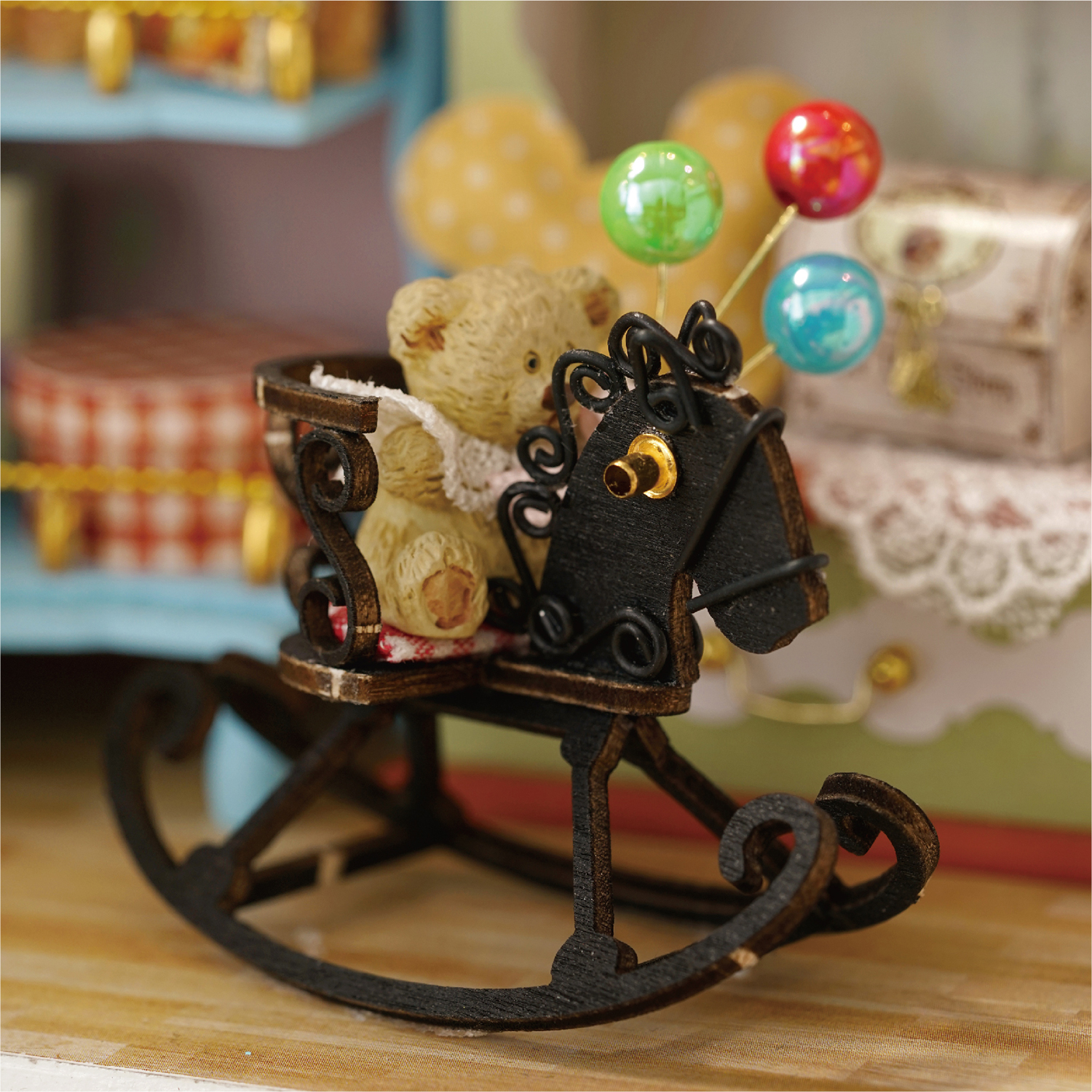 Un orsacchiotto siede in una mini carrozza a cavallo a dondolo con palloncini.