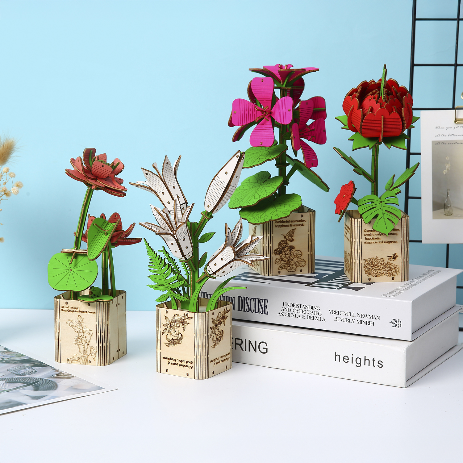Modelli di fiori in legno in vasi di legno su libri su sfondo blu.