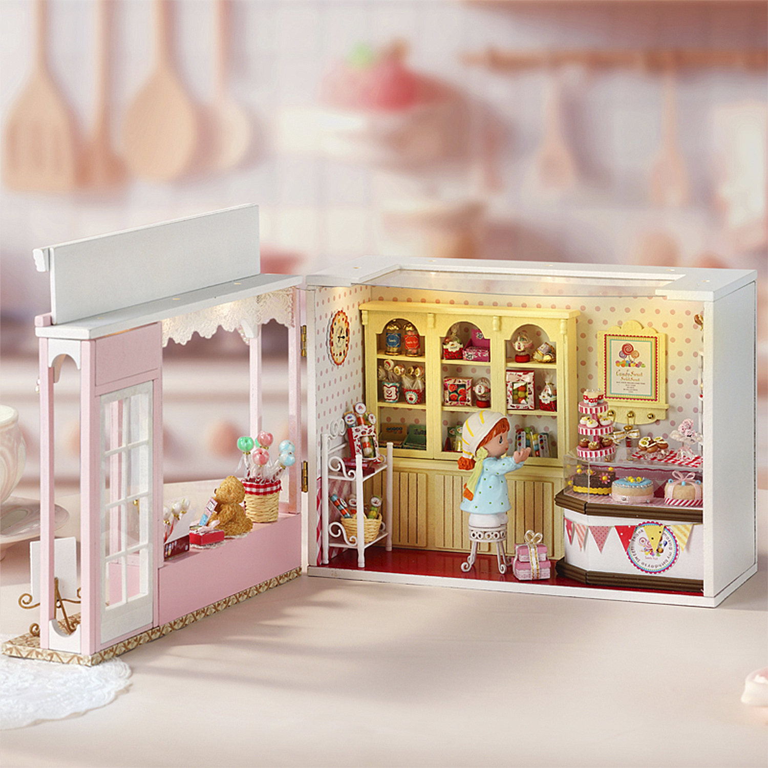 Negozio di dolci in miniatura con bambola, orsacchiotto, torte e caramelle.