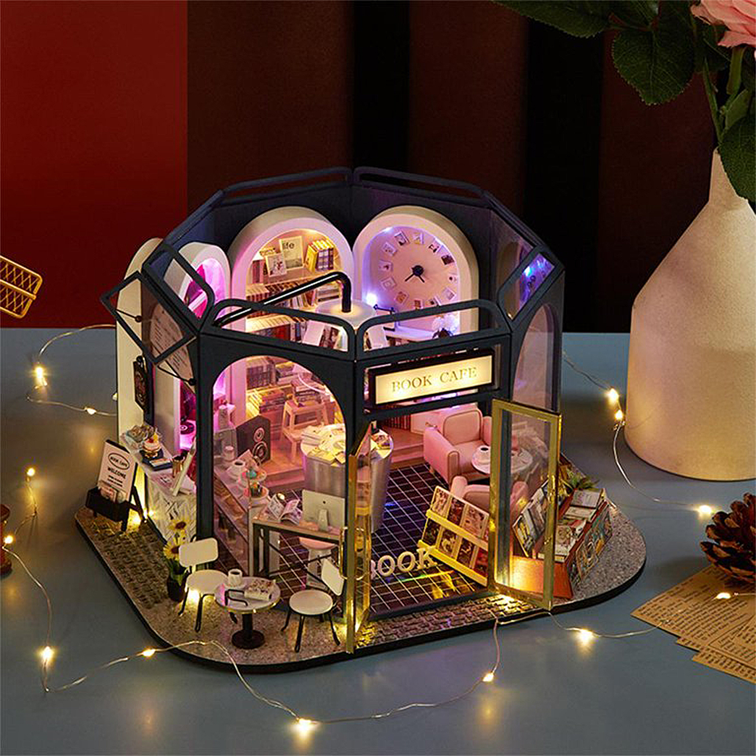 Un mini caffè letterario con luci scintillanti, mobili minuscoli e espositori di libri.