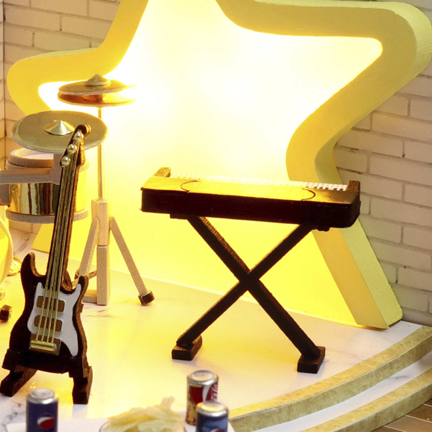 Chitarra, tastiera, batteria e lattine in miniatura davanti a una stella.
