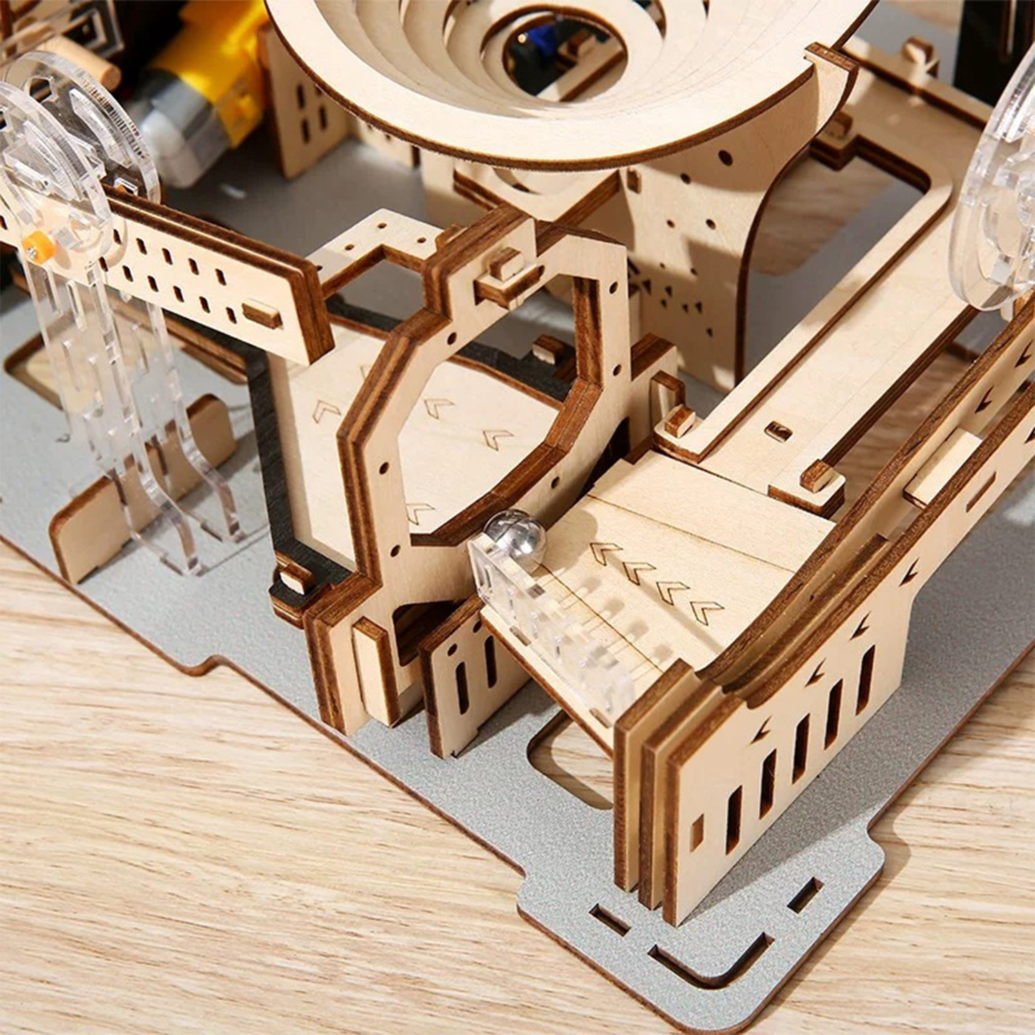 Un modello di pista di biglie in legno con parti in plastica trasparente e una biglia di metallo.