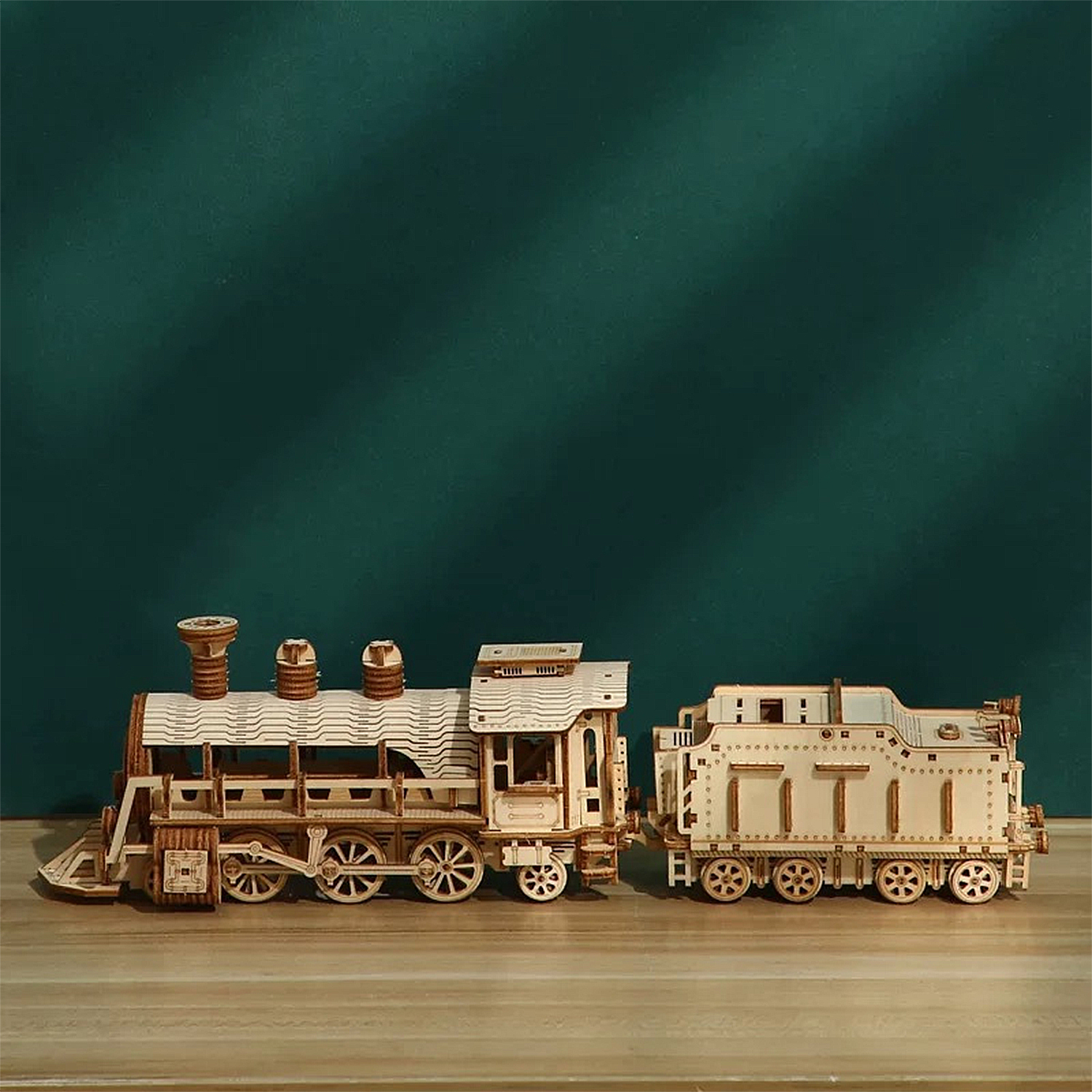Modello in legno di una locomotiva a vapore e vagone su superficie di legno.