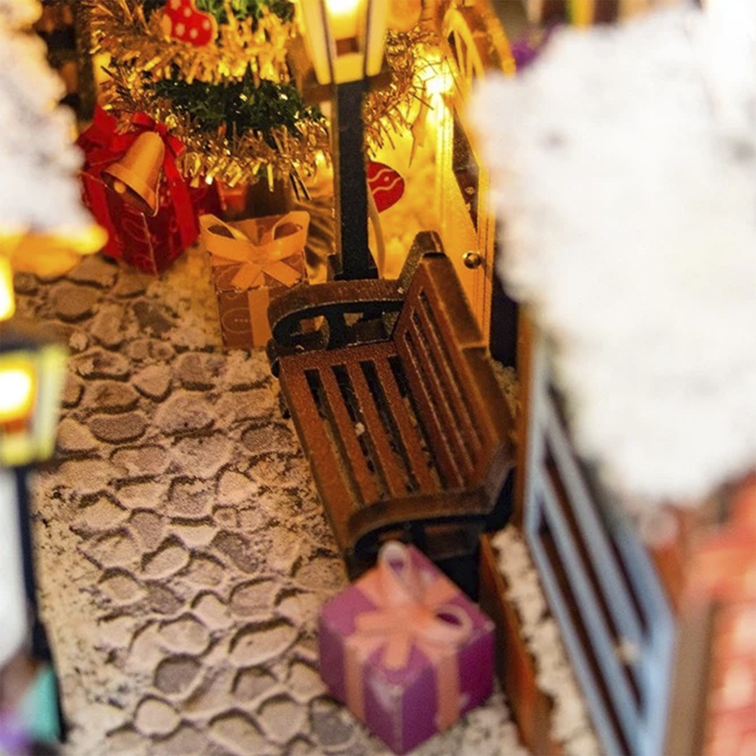 Decorazione natalizia in miniatura con regali e albero illuminato.