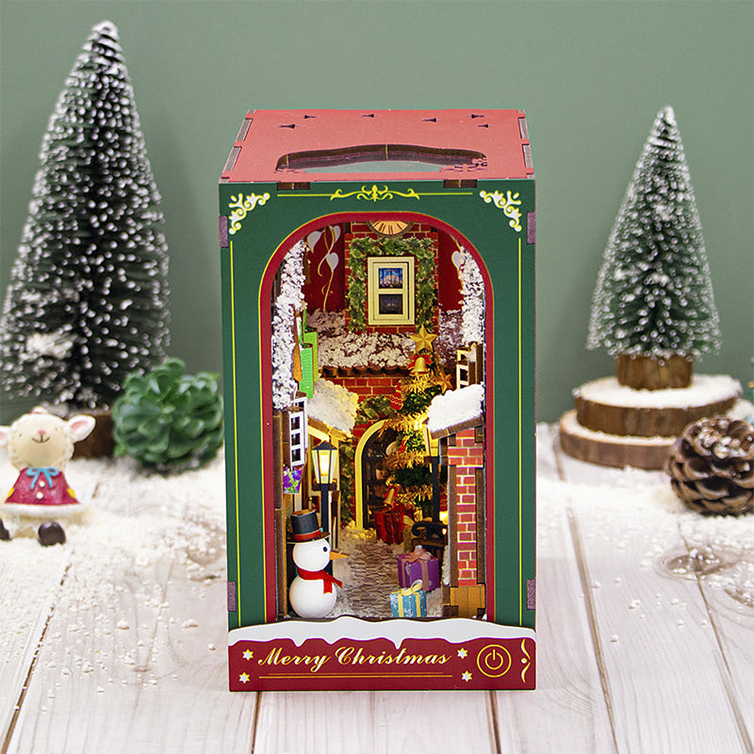 Diorama natalizio con pupazzo di neve e regali, circondato da alberi.