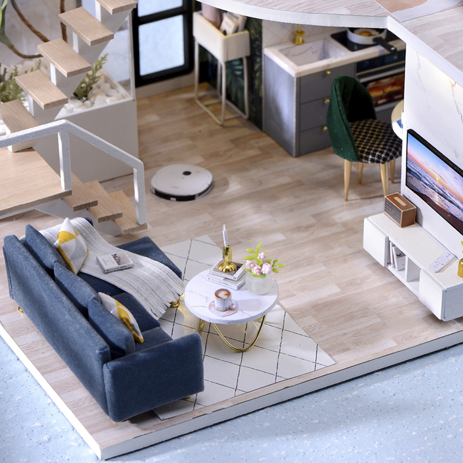Soggiorno in miniatura con divano, tavolino, scale e cucina.