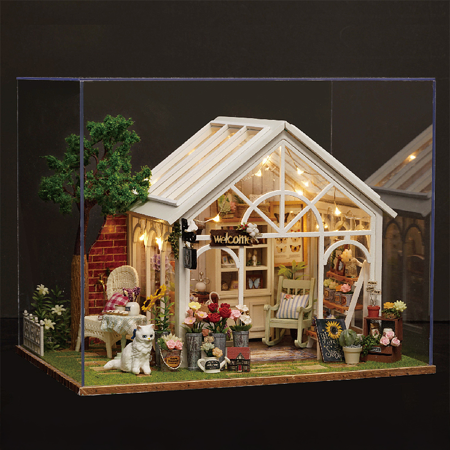 Serra in miniatura con mobili, fiori, un gatto e luci.