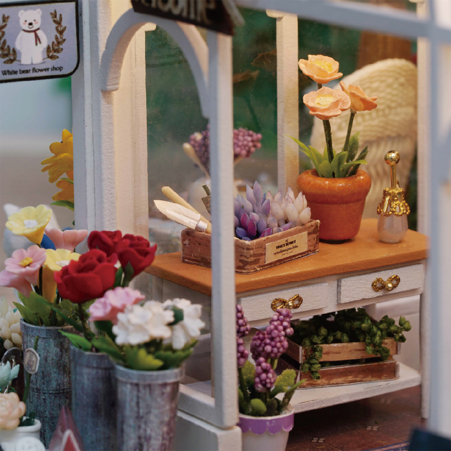 Negozio di fiori in miniatura con rose rosse, tulipani e lavanda in vaso.