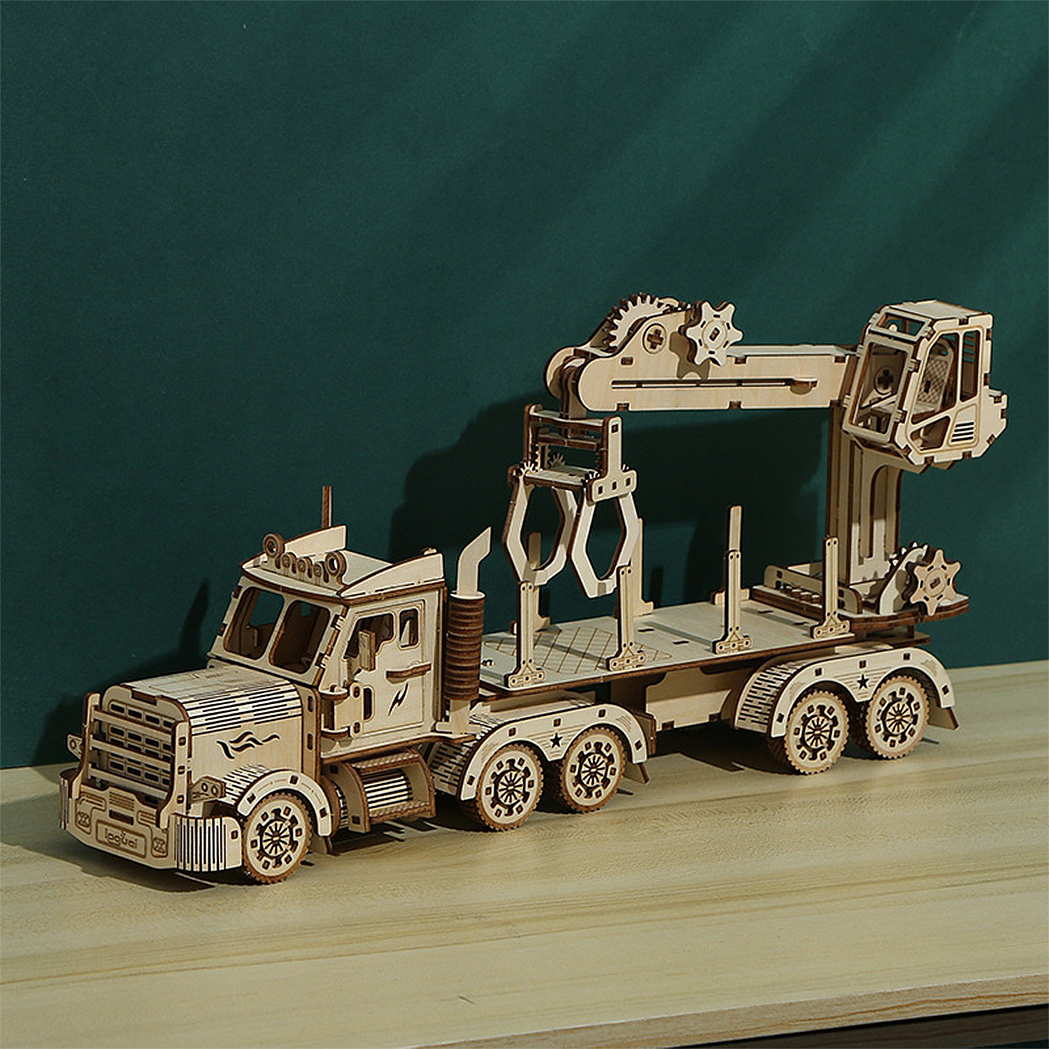 Modello in legno di un camion con gru, su un tavolo di legno.