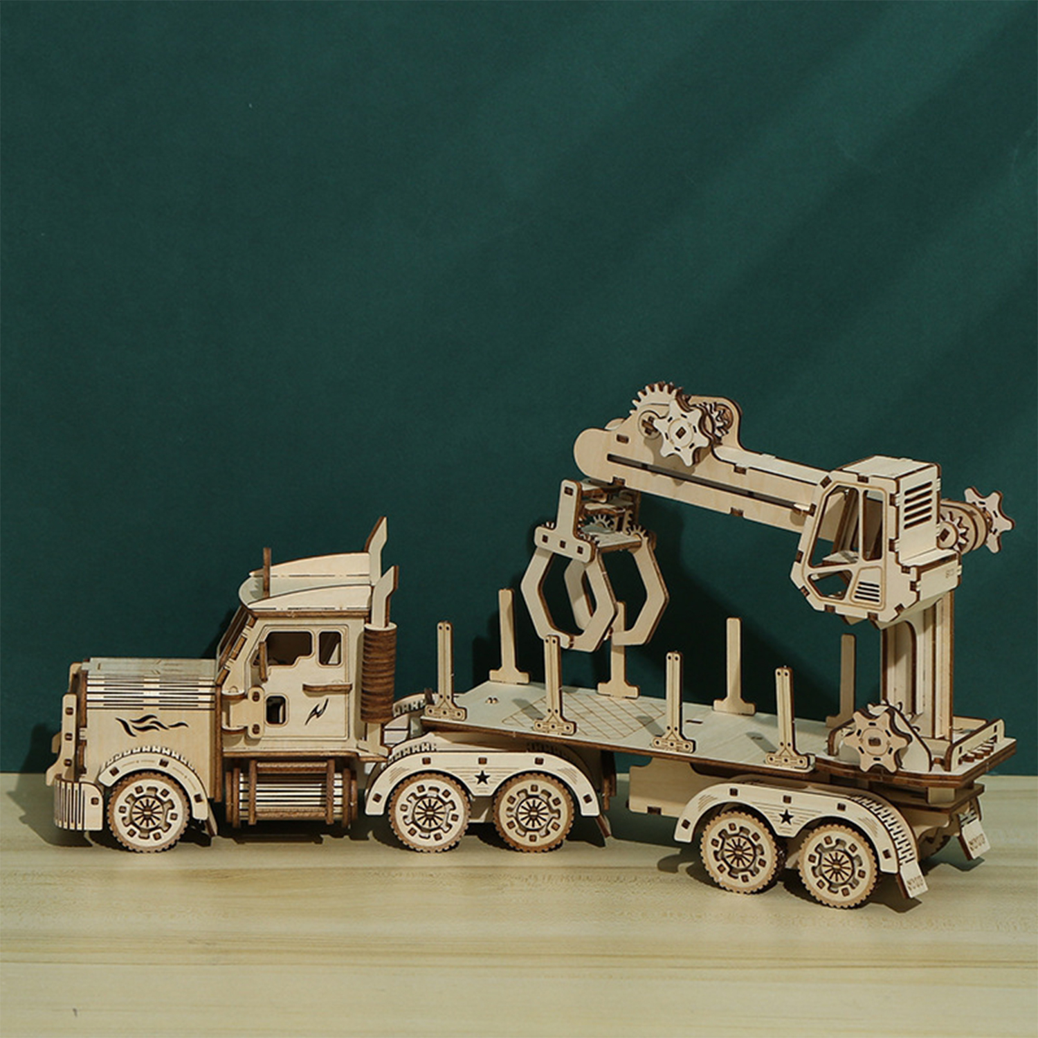 Un modello in legno di un camion per tronchi con gru è su un tavolo di legno.