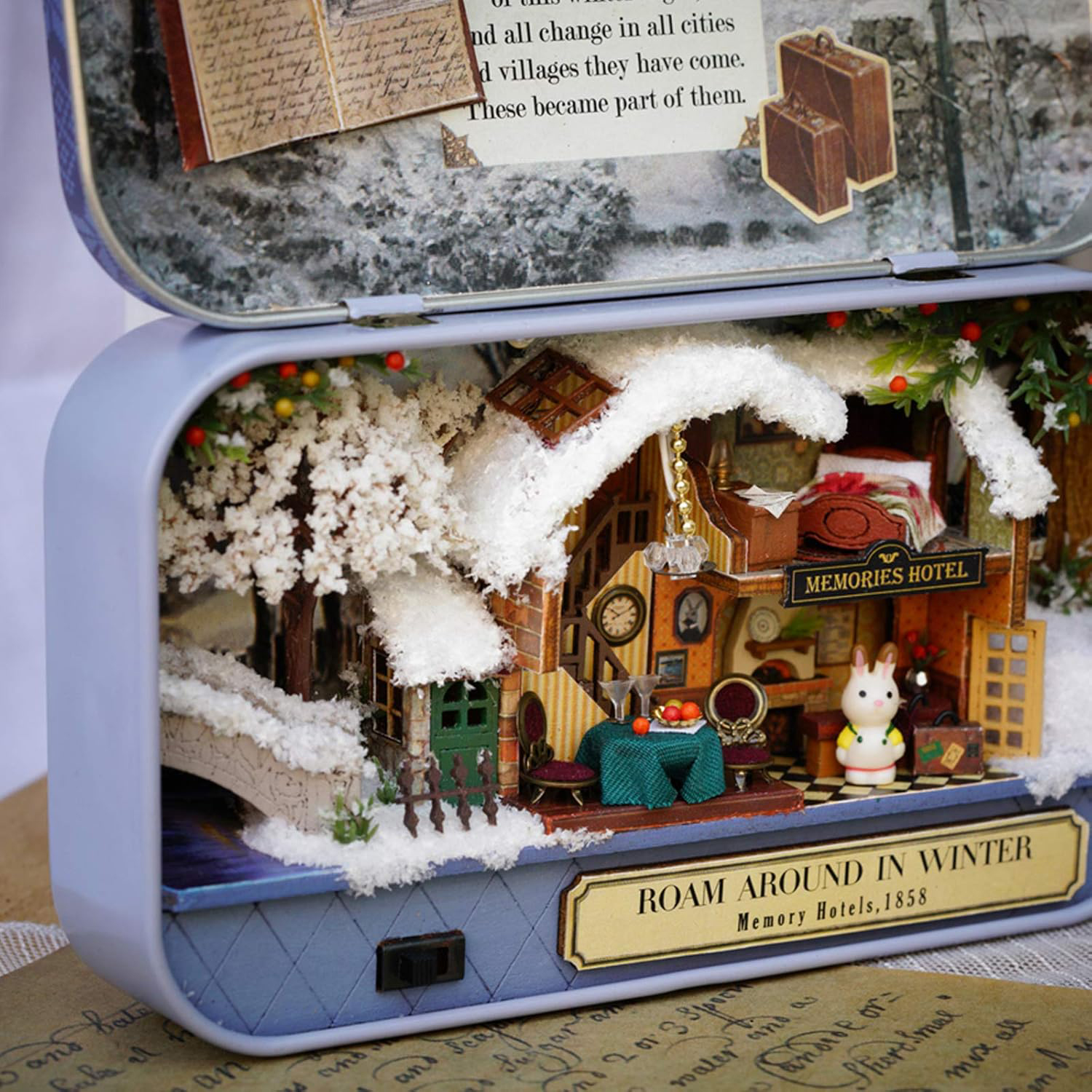 Scena invernale in miniatura con hotel, ponte e coniglietto.