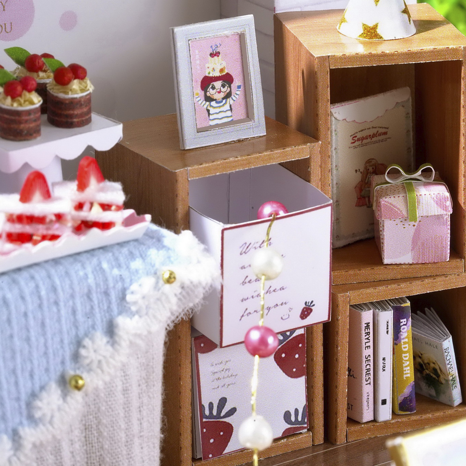 Scena in miniatura con cupcake, torta, libri e regali.