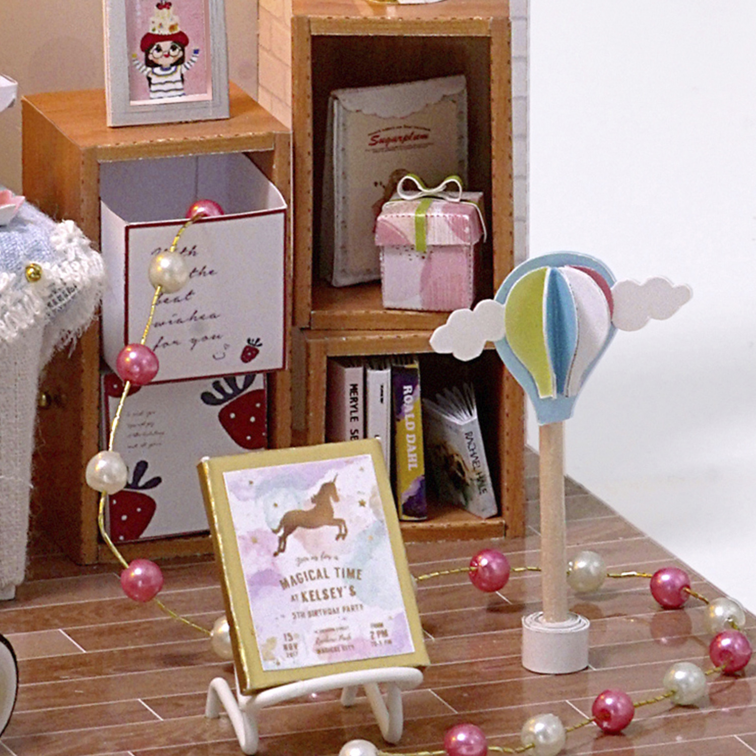 Mobile in miniatura con libri, regali e un invito di compleanno unicorno.