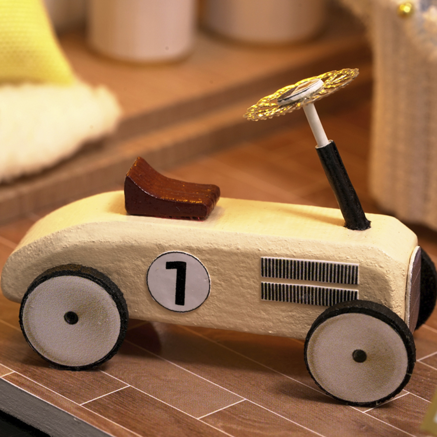Una macchinina da corsa gialla in miniatura con sedile marrone e volante dorato.