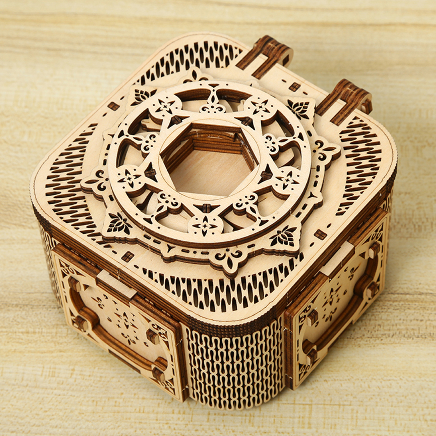 Scatola decorativa in legno con intagli intricati e coperchio aperto su sfondo di legno.