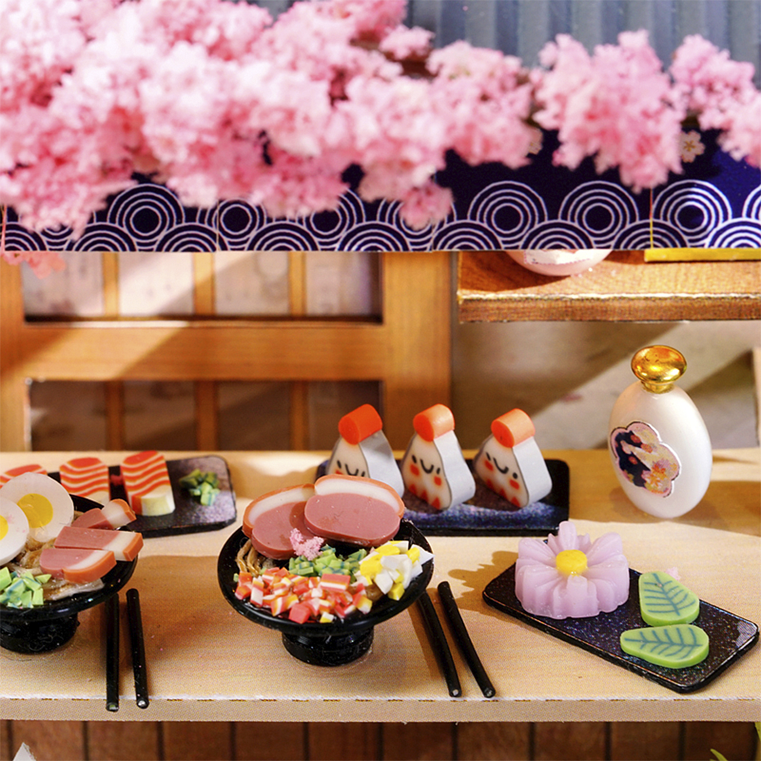Cibo giapponese in miniatura: sushi, onigiri, zuppa di noodle e fiore.