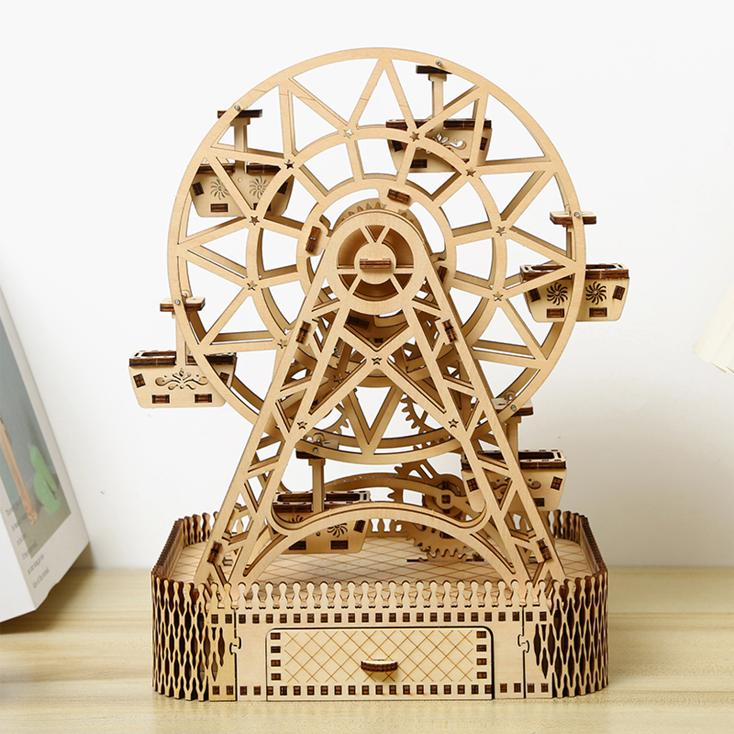 Un modello di ruota panoramica in legno con gondole su una base con recinzione.