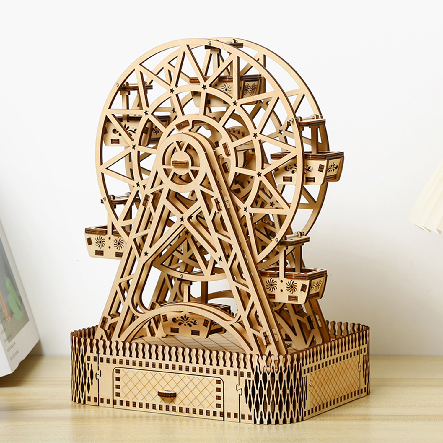 Un dettagliato modello in legno di una ruota panoramica con gondole e base ornata.