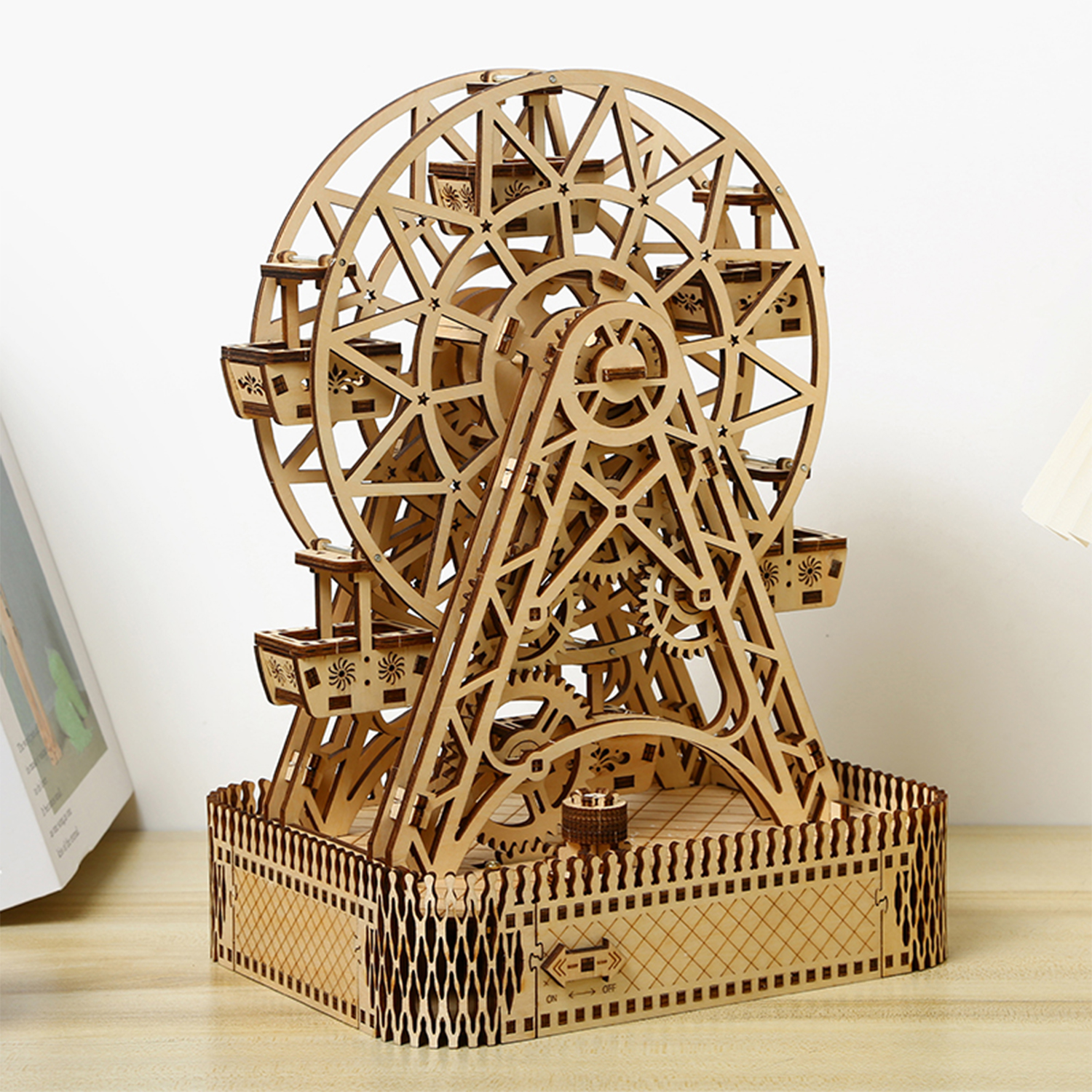 Un modello di ruota panoramica in legno con gondole e base decorativa.