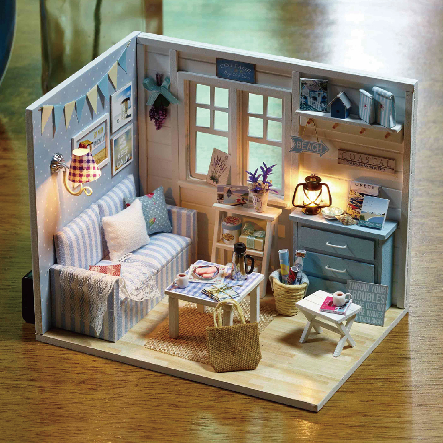 Soggiorno in miniatura con divano a righe blu e bianche, tavolo e lampade.