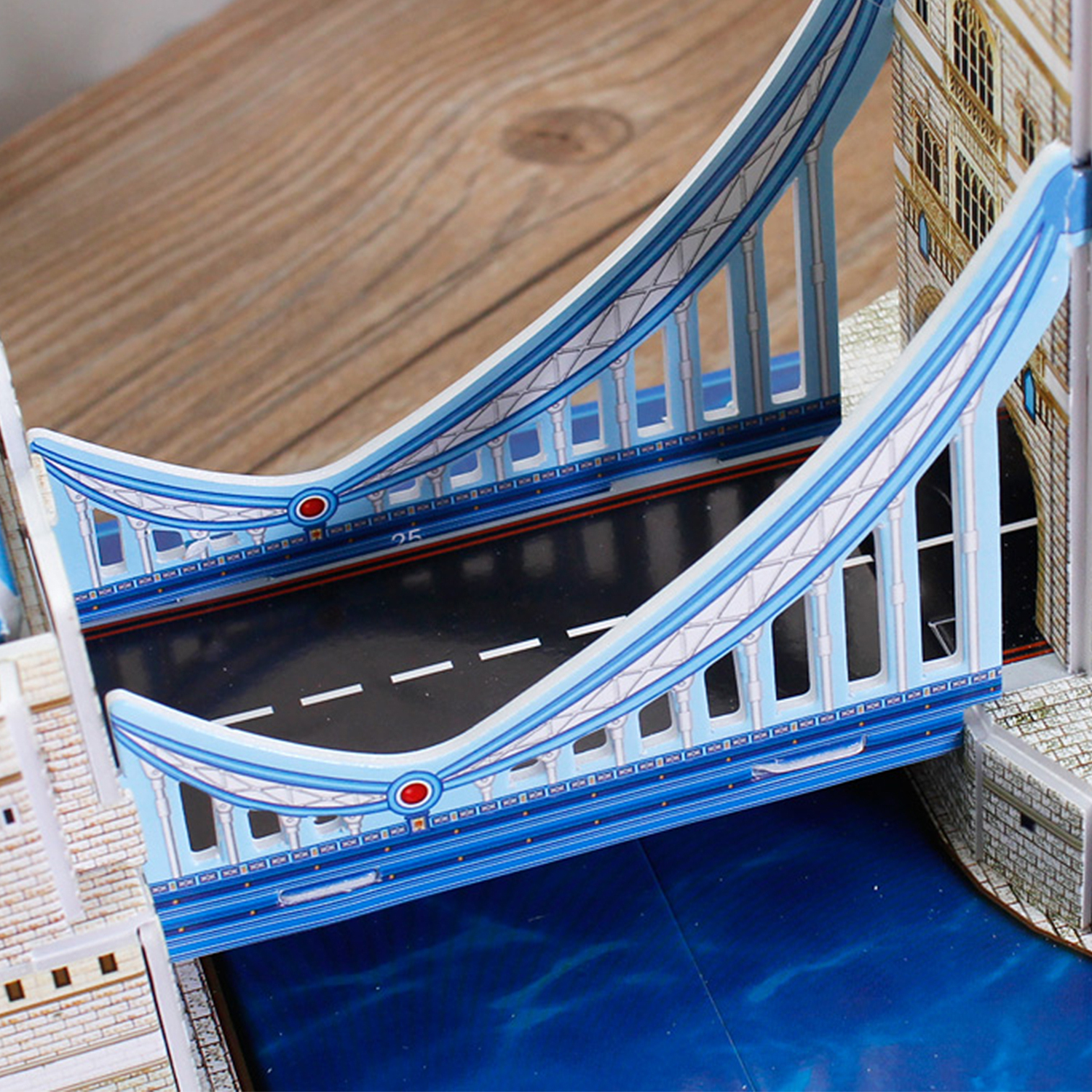 Modello di ponte sospeso blu con strada, fiume e tavolo di legno.