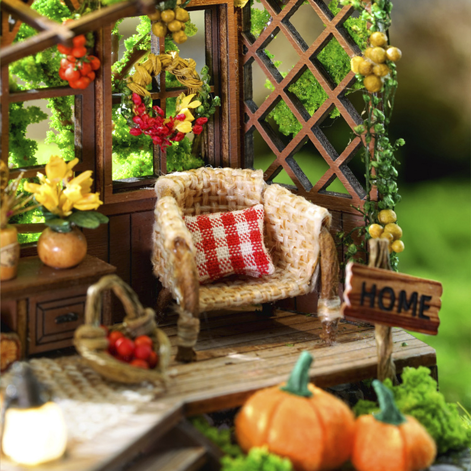 Veranda in miniatura con poltrona, zucche, fiori e cartello "Home".