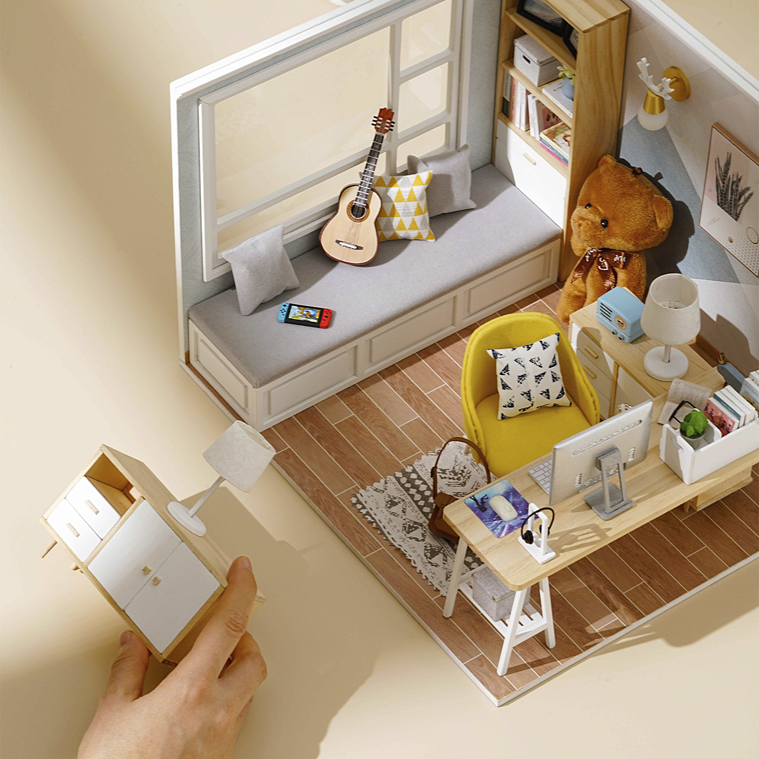 Ufficio in miniatura con chitarra, orsacchiotto, scrivania e computer.