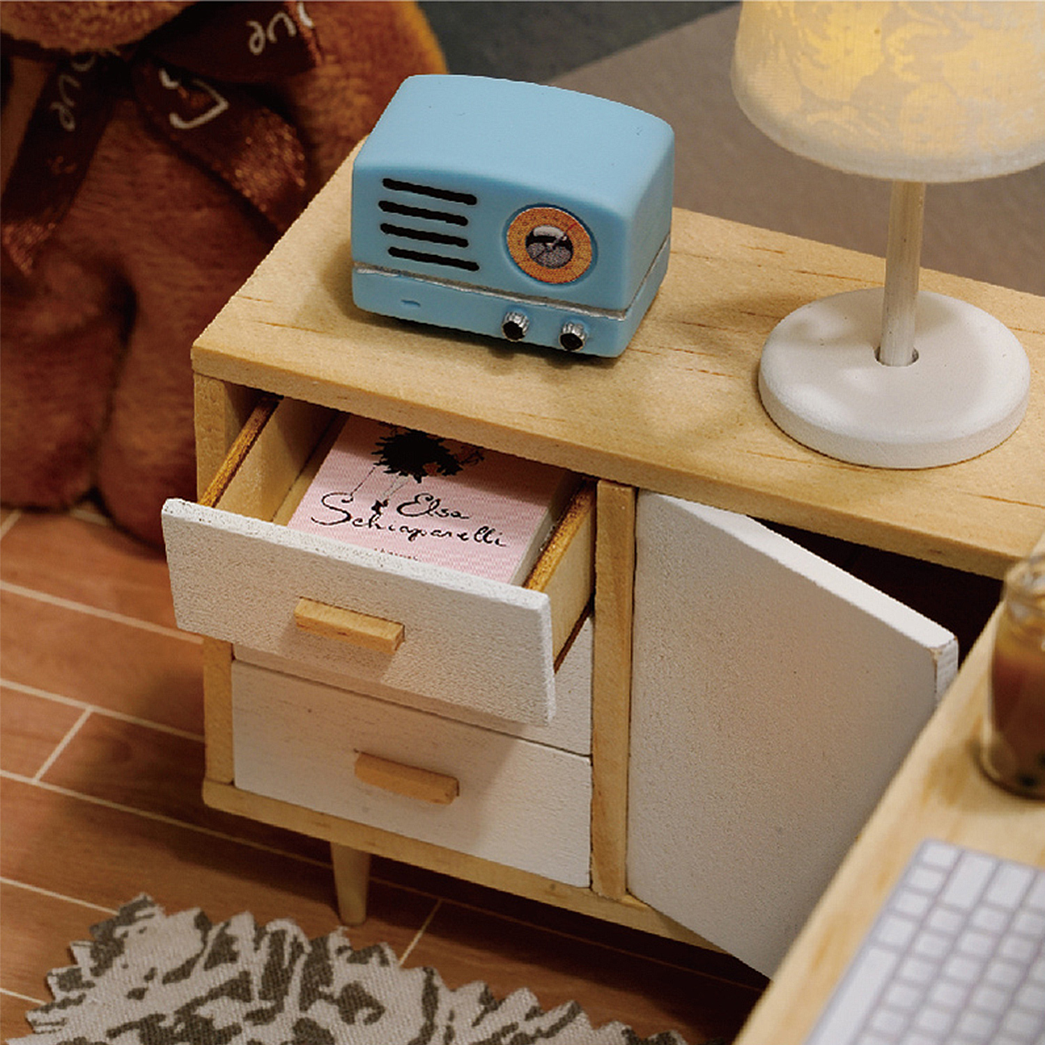Un comò in miniatura con una miniatura "radio" blu e una lampada.