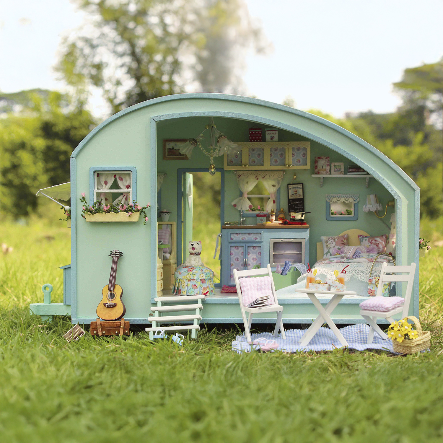 Una scena di roulotte in miniatura con chitarra, letto e tavolo da picnic.